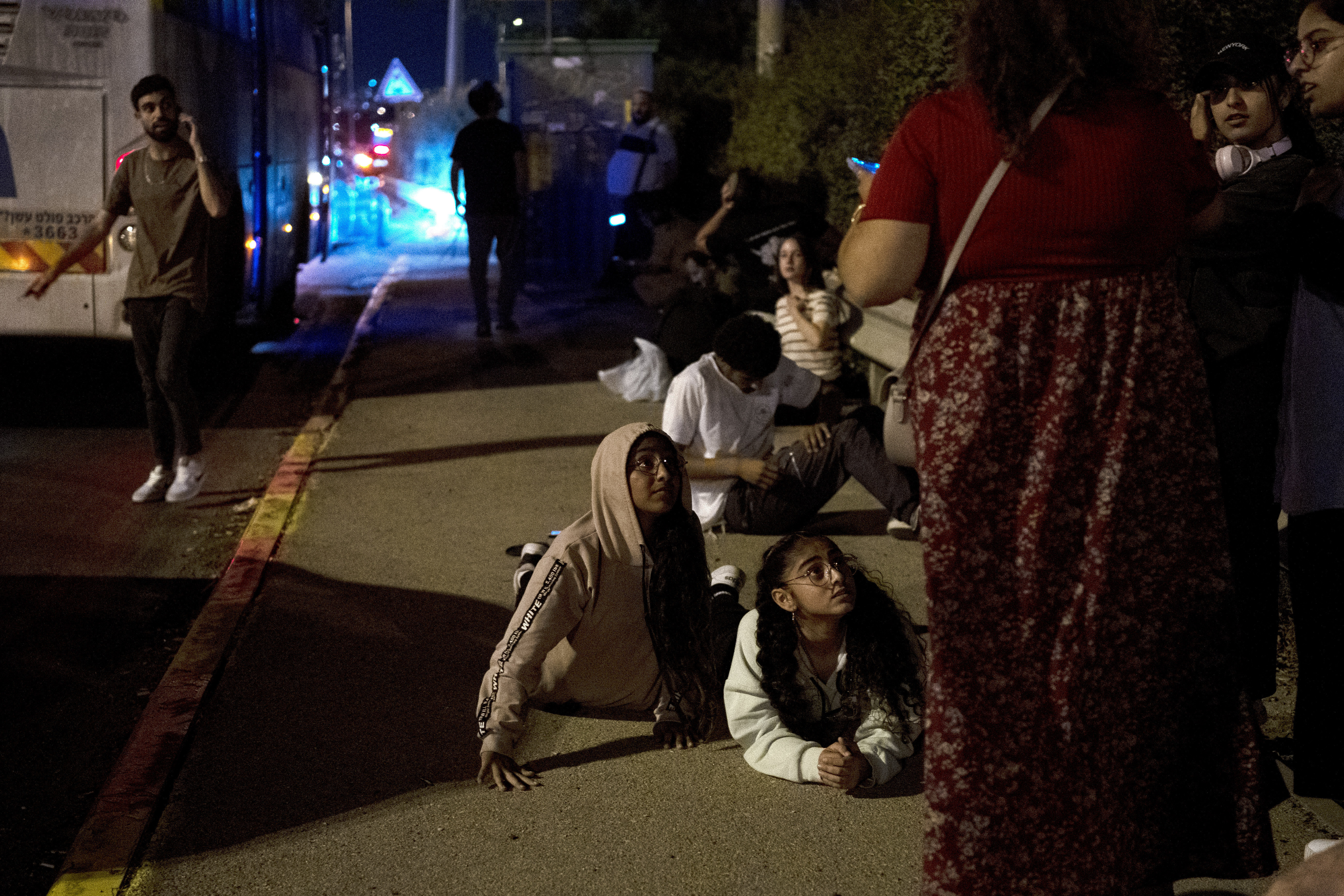 FILE - Israelis wait to re-board their bus after projectiles were launched from Iran are being intercepted in the skies over in Rosh HaAyin, Israel, Tuesday, Oct. 1, 2024. (AP Photo/Maya Alleruzzo, File)