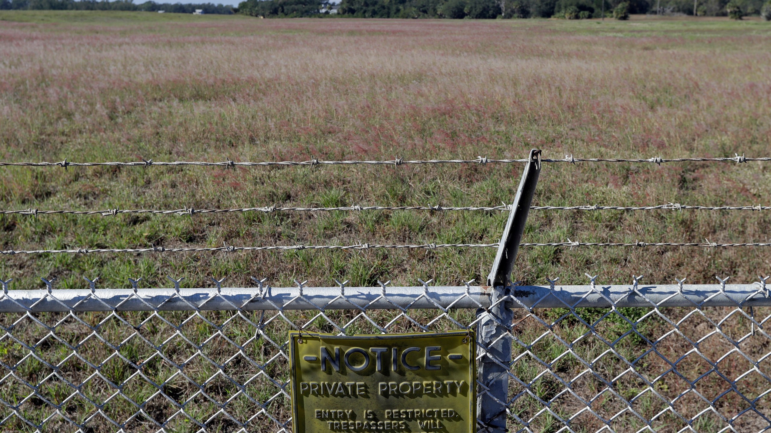 FILE - A private property sign is attached to a fence outside the old Stauffer chemical plant toxic waste dump site in Tarpon Springs, Fla., on Nov. 30, 2017. (AP Photo/Chris O'Meara, File)