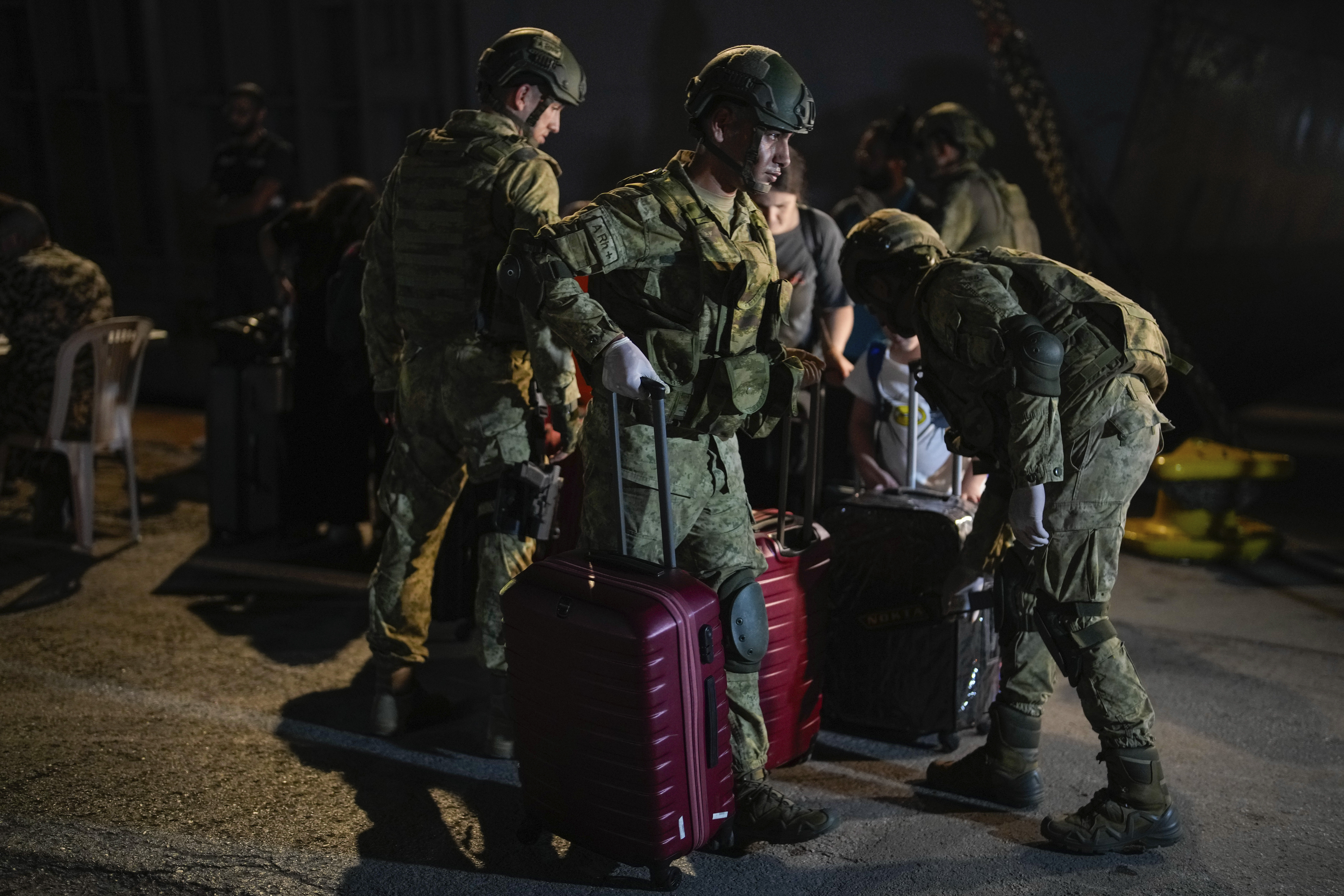 Turkish military personnel carry luggage of Turkish citizens to be evacuated on Turkish military ships from Lebanon to Turkey, in Beirut port, Wednesday, Oct. 9, 2024. (AP Photo/Emrah Gurel)