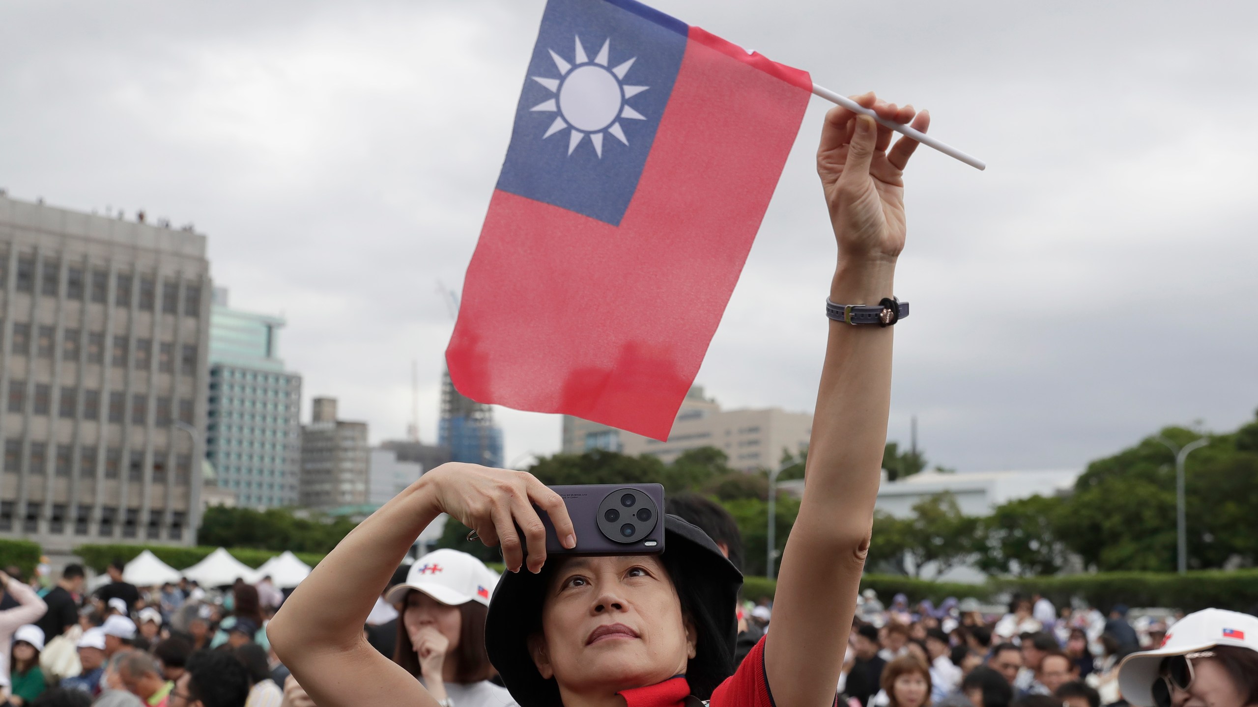 A person poses with Taiwan's national flag for a photo during National Day celebrations in front of the Presidential Building in Taipei, Taiwan, Thursday, Oct. 10, 2024. (AP Photo/Chiang Ying-ying)