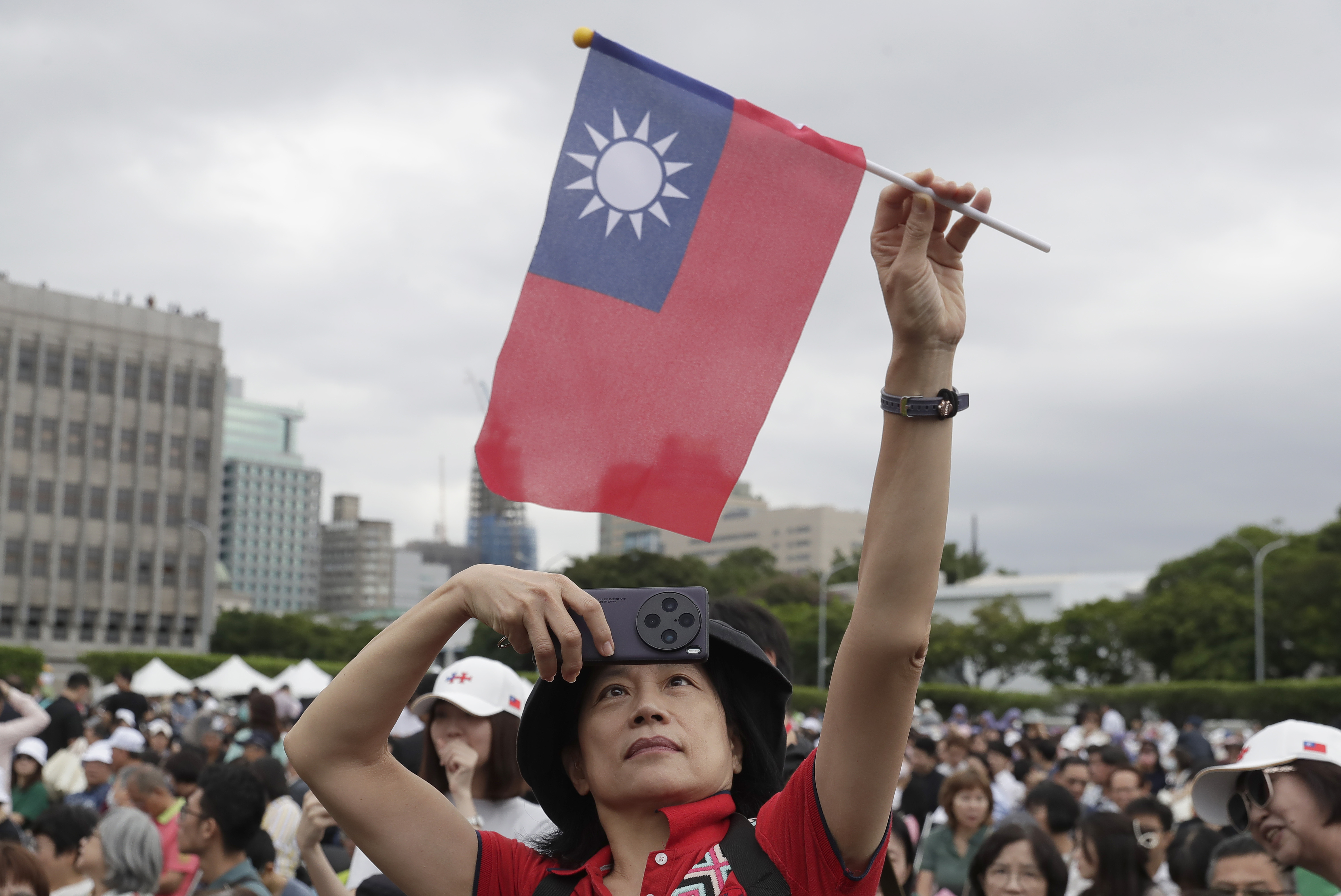 A person poses with Taiwan's national flag for a photo during National Day celebrations in front of the Presidential Building in Taipei, Taiwan, Thursday, Oct. 10, 2024. (AP Photo/Chiang Ying-ying)