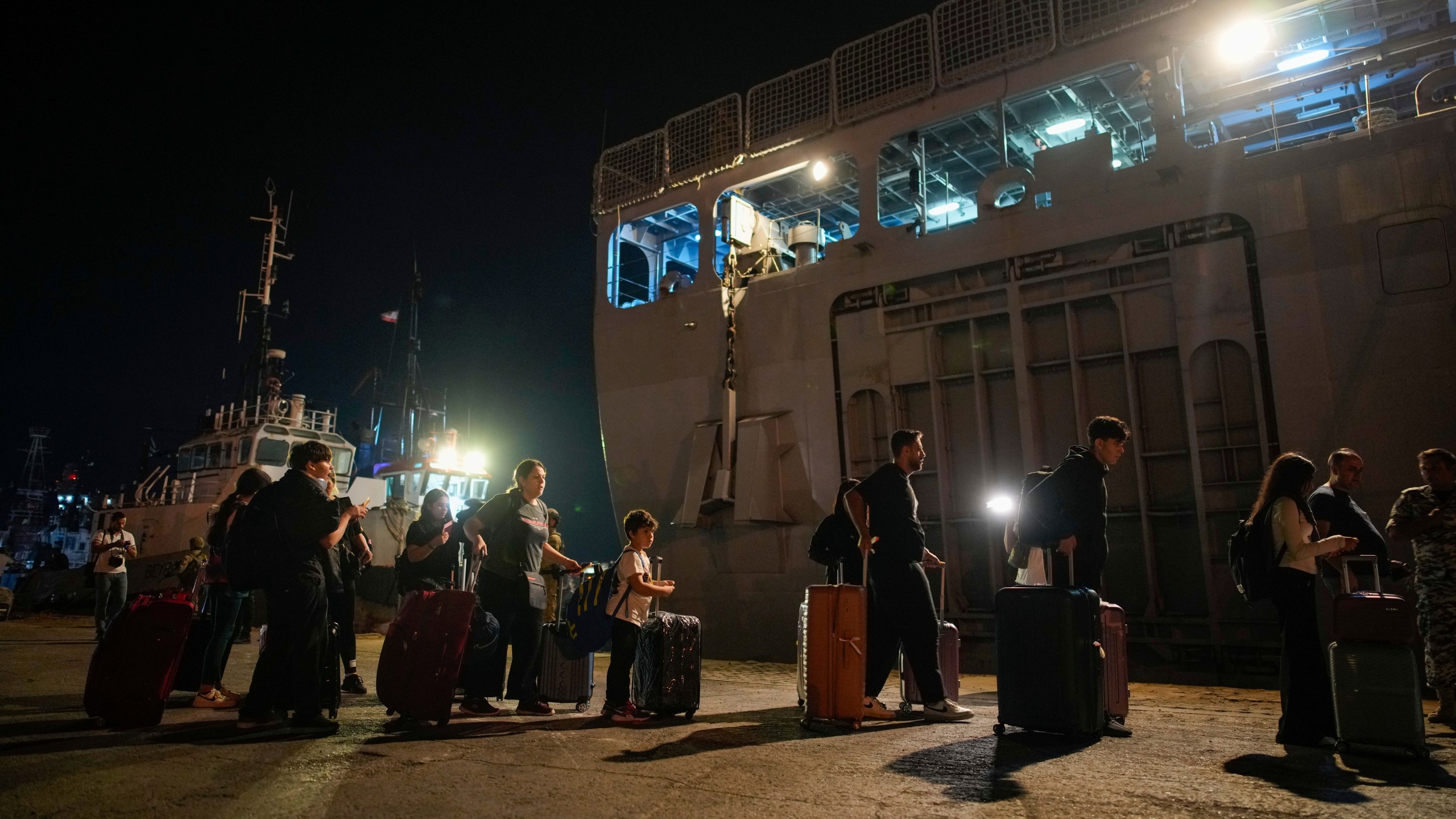 Turkish citizens walk to board Turkish military ships evacuating them from Lebanon to Turkey, in Beirut port on Wednesday, Oct. 9, 2024. (AP Photo/Emrah Gurel)