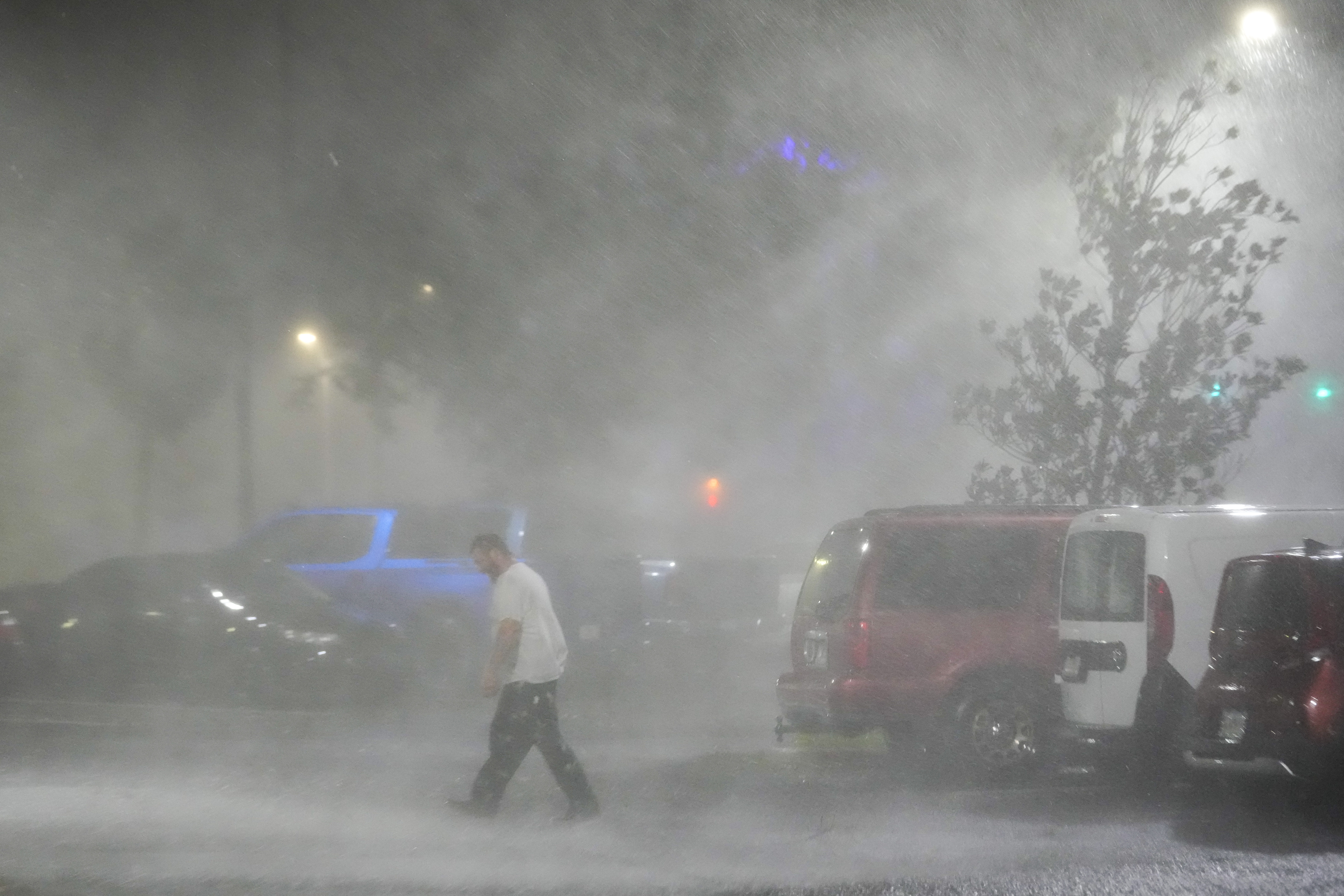 Max Watts, of Buford, Ga., walks in the parking lot to check on a trailer parked outside the hotel where he is riding out Hurricane Milton with coworkers, Wednesday, Oct. 9, 2024, in Tampa, Fla. Watts, who works for a towing company, was deployed with colleagues to Florida to aid in the aftermath of the storm. (AP Photo/Julio Cortez)