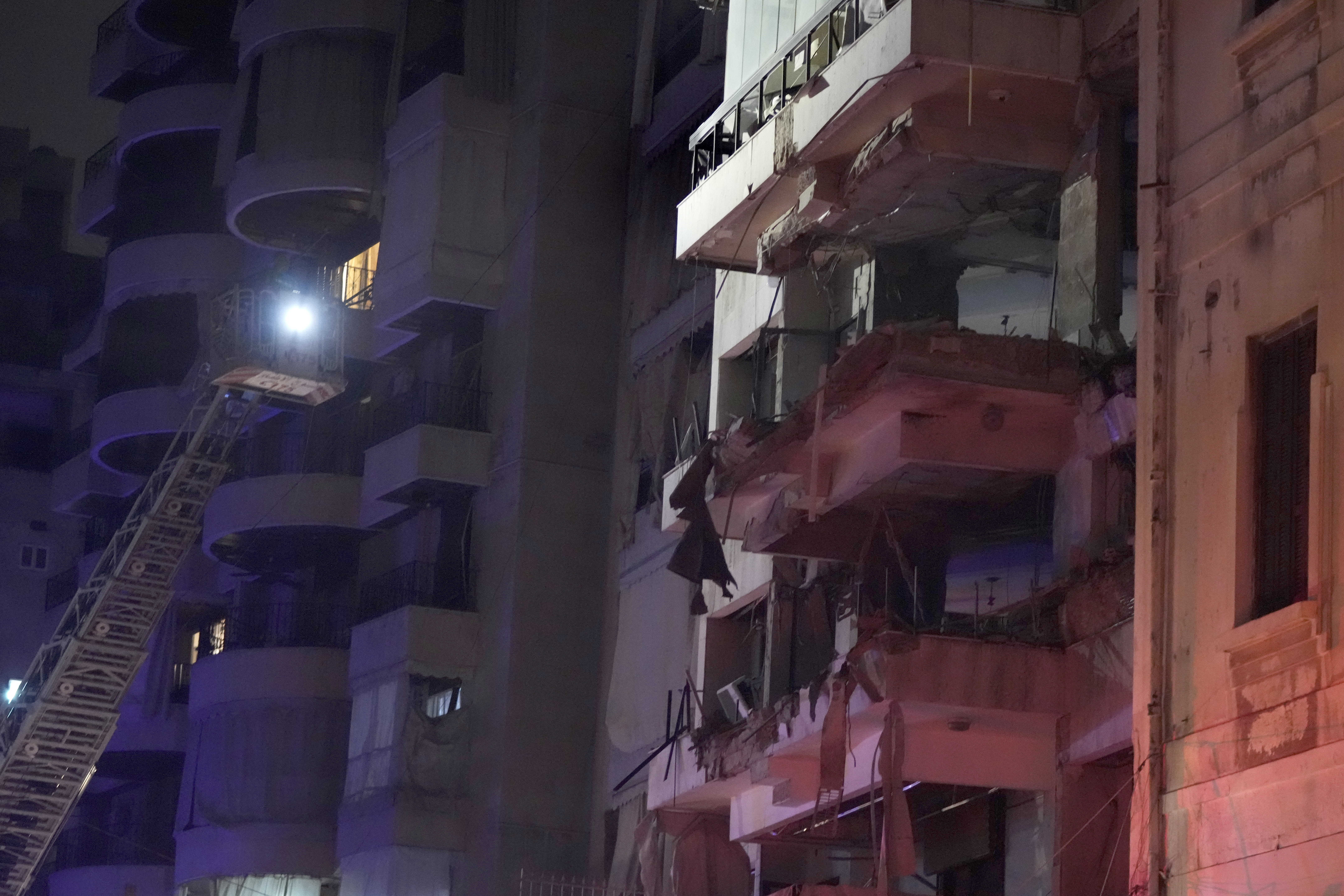 Rescue workers standing on a crane check a destroyed building hit by an Israeli airstrike in central Beirut, Lebanon, Thursday, Oct. 10, 2024. (AP Photo/Hassan Ammar)