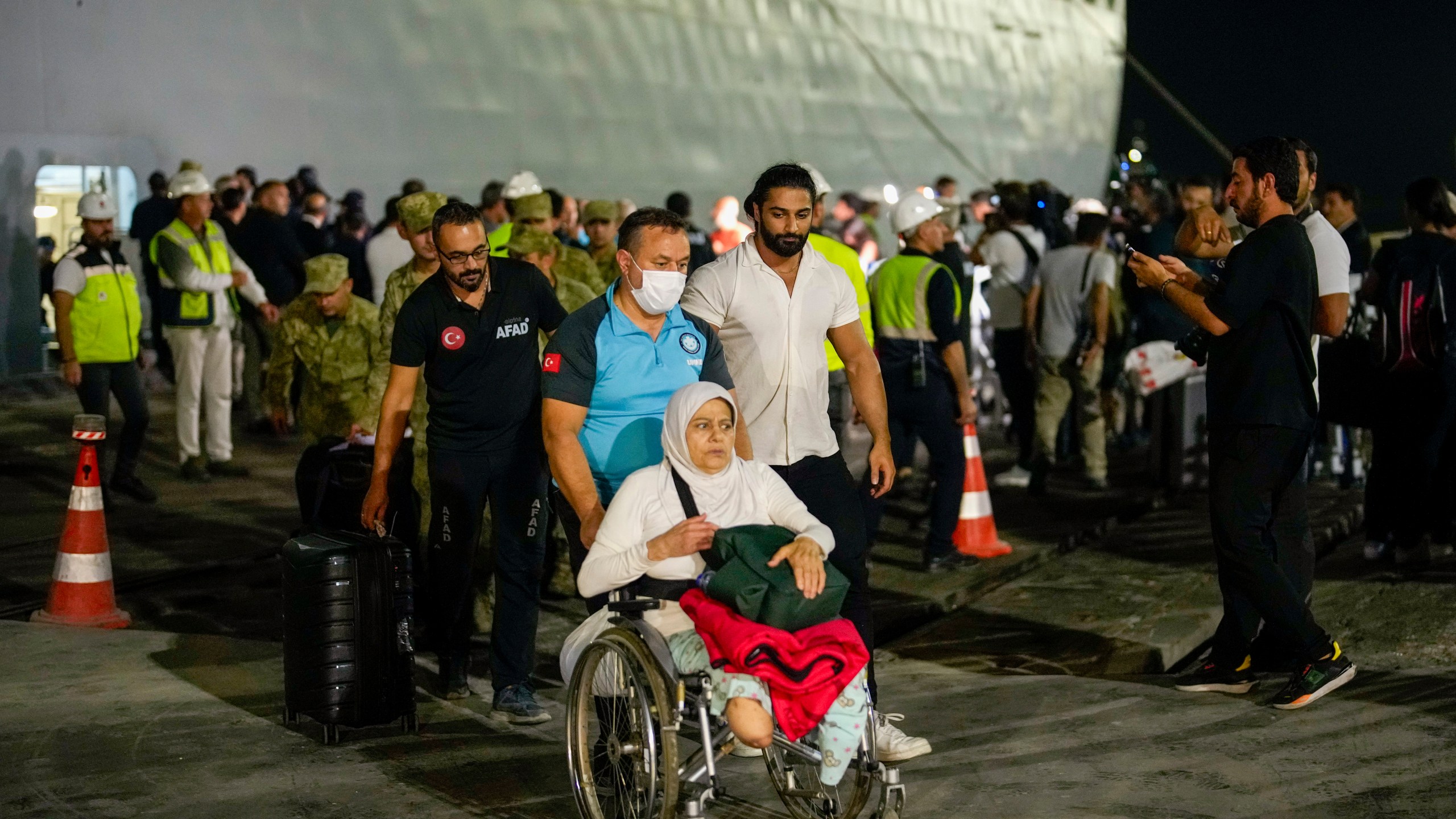 People, mostly Turkish nationals, disembark from Turkish TCG Sancaktar military ship after being evacuated from Lebanon's capital Beirut to Turkey, in Mersin port, southern Turkey, early Friday, Oct. 11, 2024. (AP Photo/Emrah Gurel)