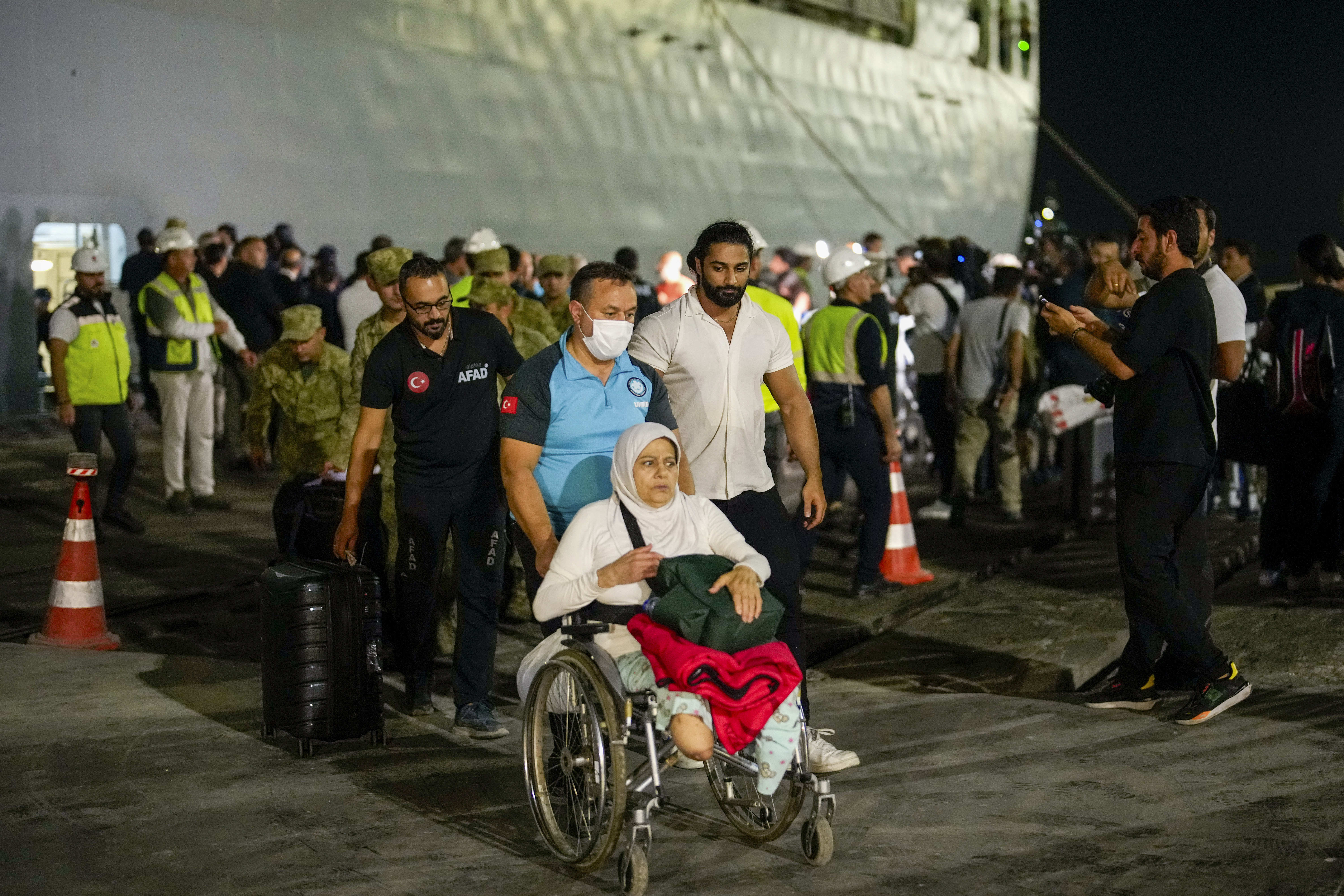 People, mostly Turkish nationals, disembark from Turkish TCG Sancaktar military ship after being evacuated from Lebanon's capital Beirut to Turkey, in Mersin port, southern Turkey, early Friday, Oct. 11, 2024. (AP Photo/Emrah Gurel)