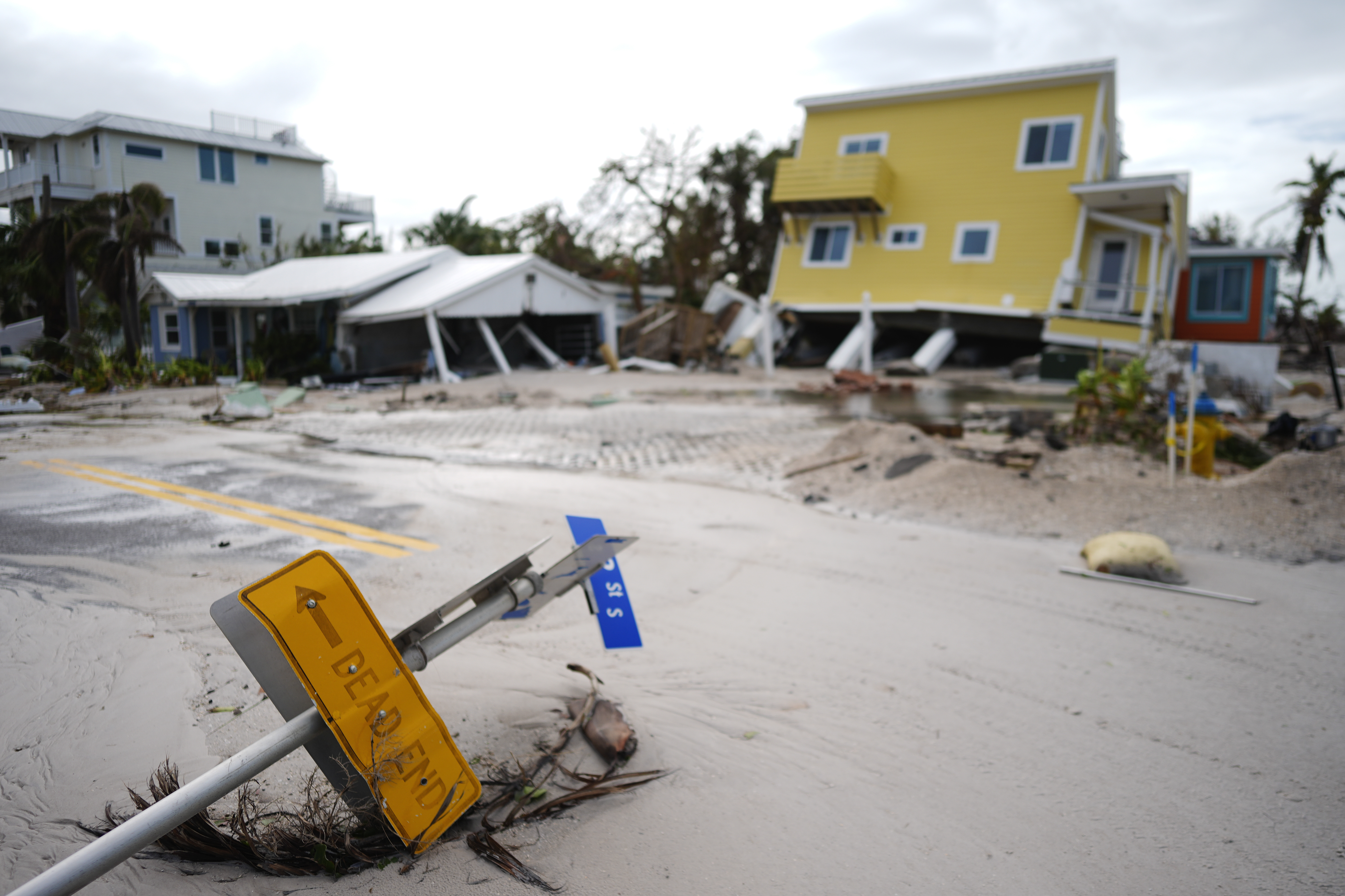 FILE - A house sits toppled off its stilts after the passage of Hurricane Milton, alongside an empty lot where a home was swept away by Hurricane Helene, in Bradenton Beach on Anna Maria Island, Fla., Oct. 10, 2024. (AP Photo/Rebecca Blackwell, File)