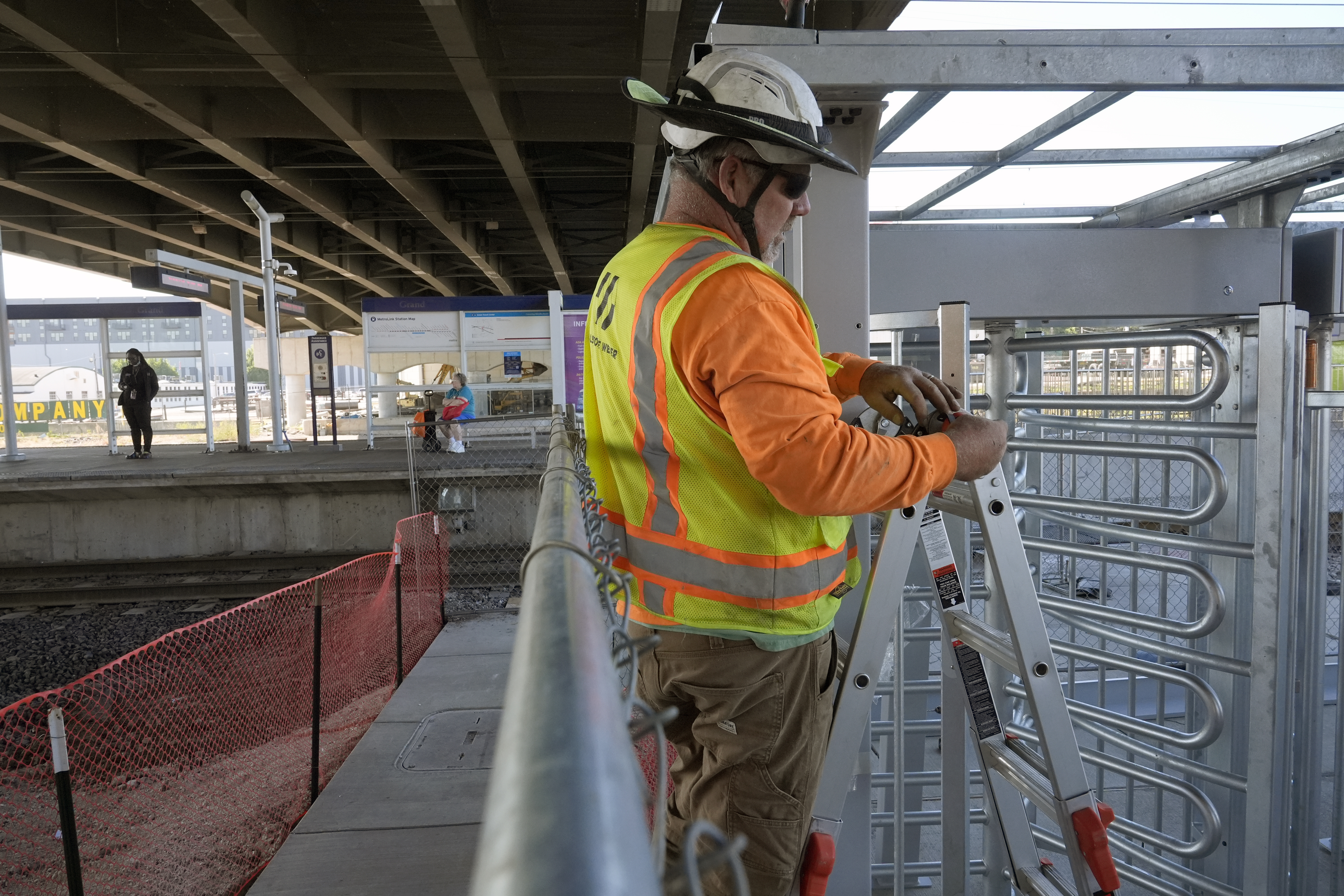 Gary Baalman with Millstone Weber construction works to install metal a gate that will prevent customers from entering a MetroLink platform without a valid fare card Wednesday, Oct. 9, 2024, in St. Louis. (AP Photo/Jeff Roberson)