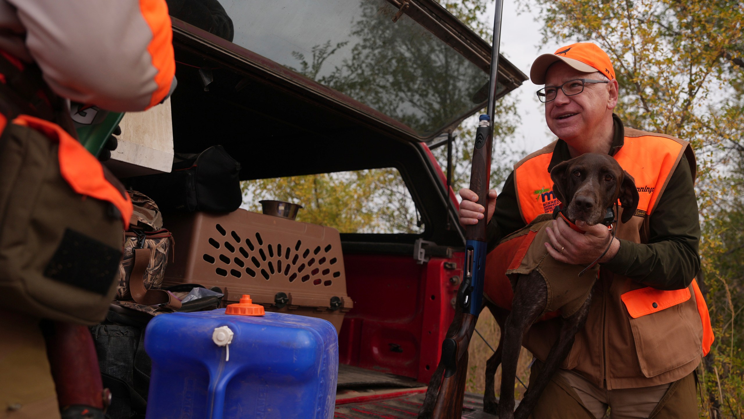 Minnesota Governor and Democratic Vice Presidential candidate Tim Walz holds Matt Kucharski's dog Libby, a 6-year-old German Shorthaired Pointer, to give her a drink during the annual Minnesota Governor's Pheasant Hunting Opener, Saturday, Oct. 12, 2024, near Sleepy Eye, Minn. (Anthony Souffle/Star Tribune via AP)