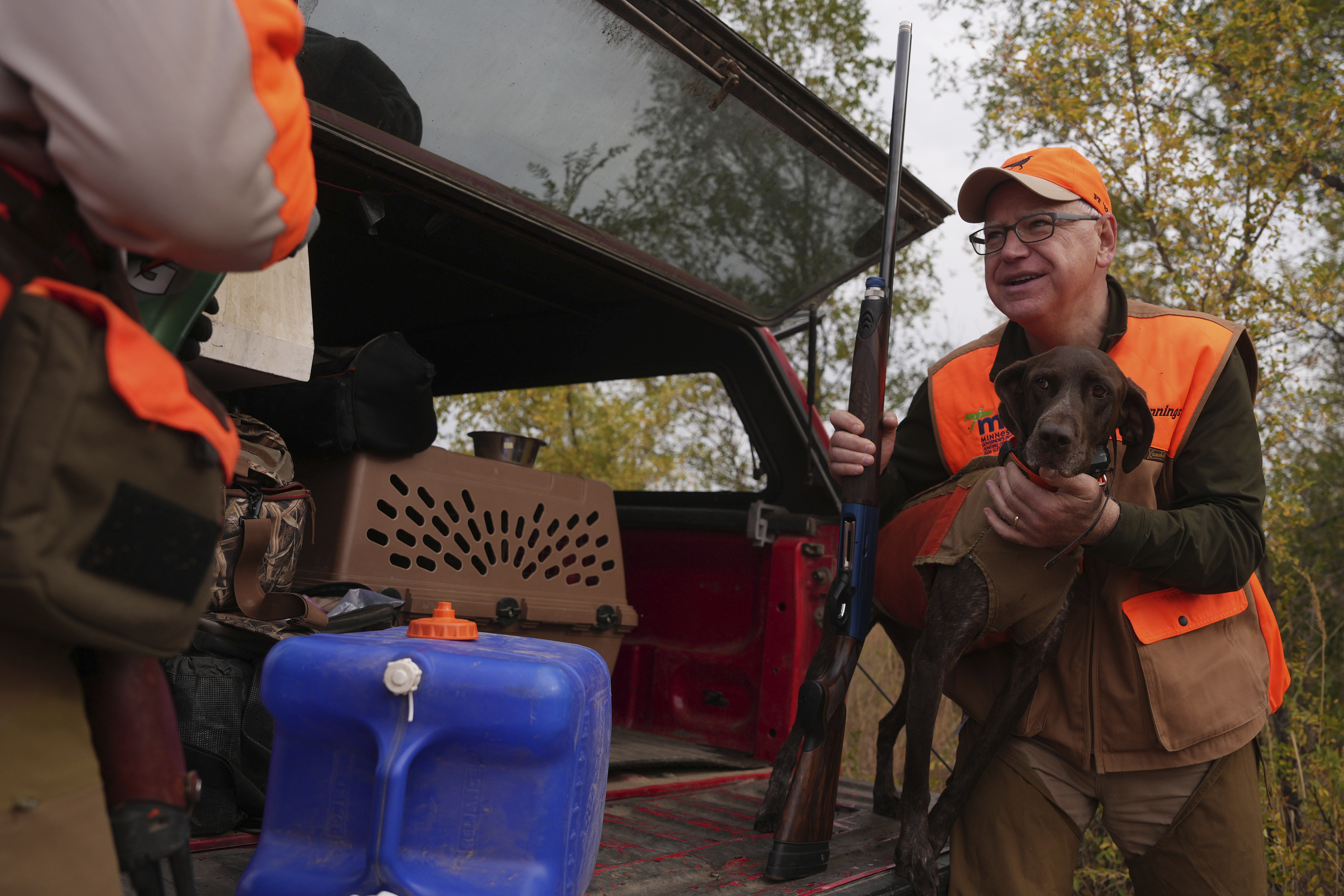 Minnesota Governor and Democratic Vice Presidential candidate Tim Walz holds Matt Kucharski's dog Libby, a 6-year-old German Shorthaired Pointer, to give her a drink during the annual Minnesota Governor's Pheasant Hunting Opener, Saturday, Oct. 12, 2024, near Sleepy Eye, Minn. (Anthony Souffle/Star Tribune via AP)