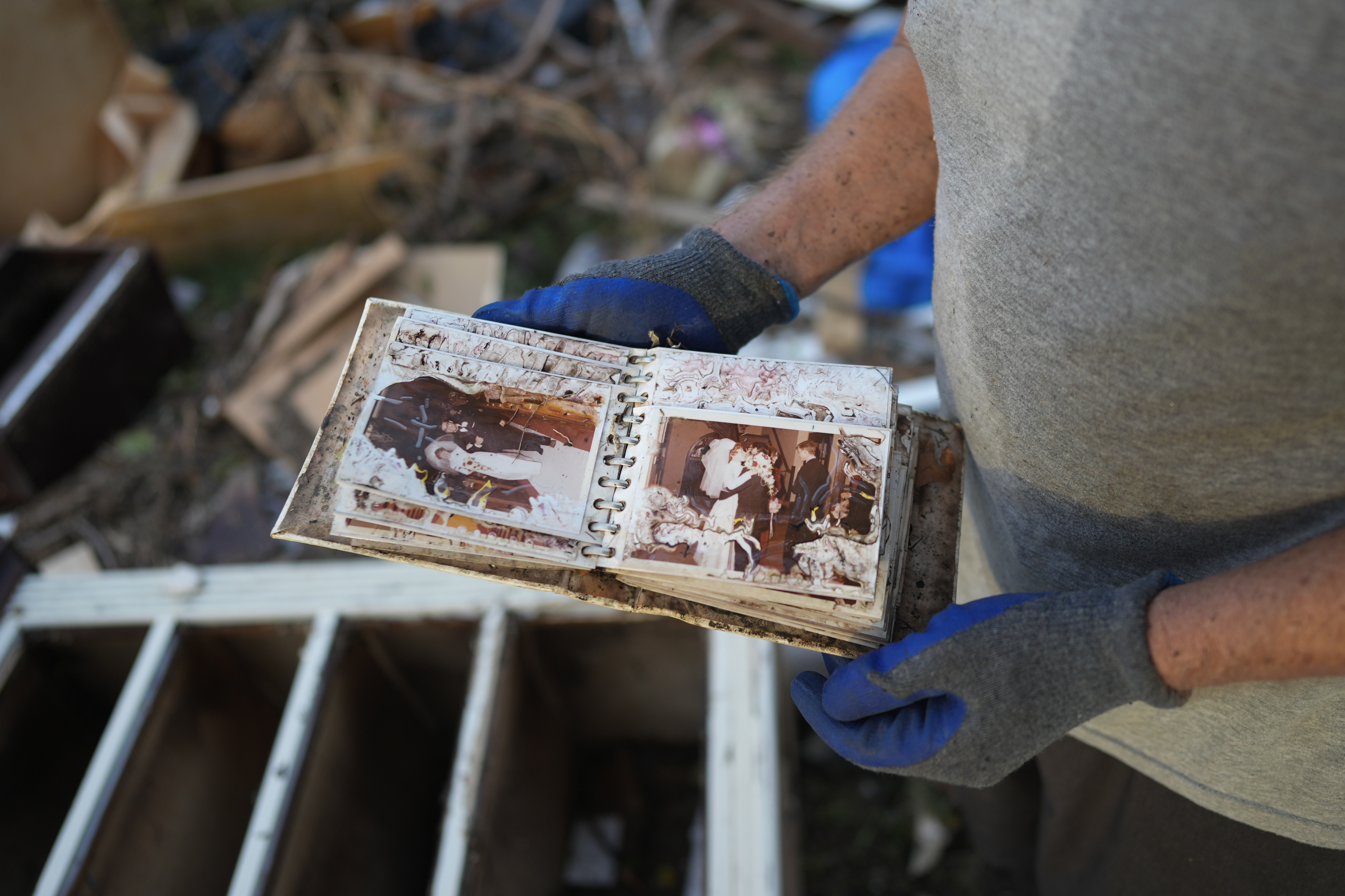 Robert Turick, 68, finds a water-damaged album of wedding photos in the debris from other homes swept into his yard by Hurricane Milton storm surge, in Englewood, Fla., Friday, Oct. 11, 2024. (AP Photo/Rebecca Blackwell)