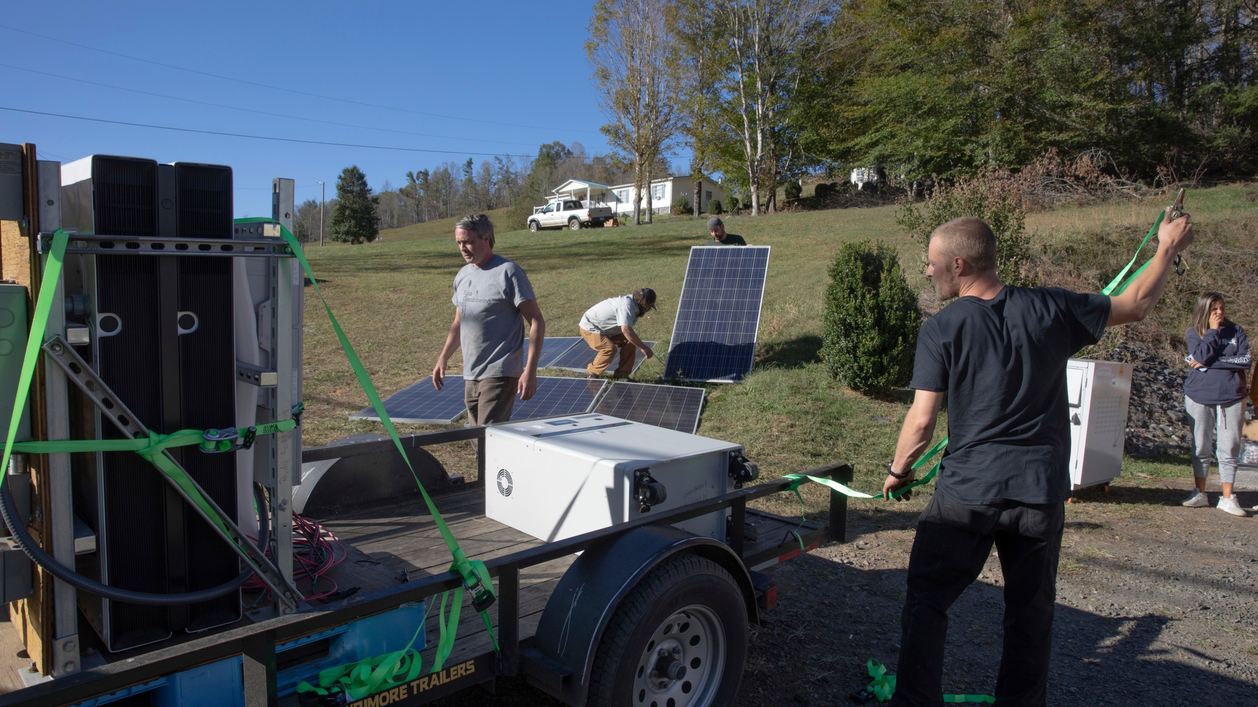 Hayden Wilson, left, Jonathan Bowen, second from left, Alexander Pellersels second from right, and Henry Kovacs, right, install a mobile power system for a resource hub in Tipton Hill, N.C. on Oct. 9, 2024. (AP Photo/Gabriela Aoun Angueria)