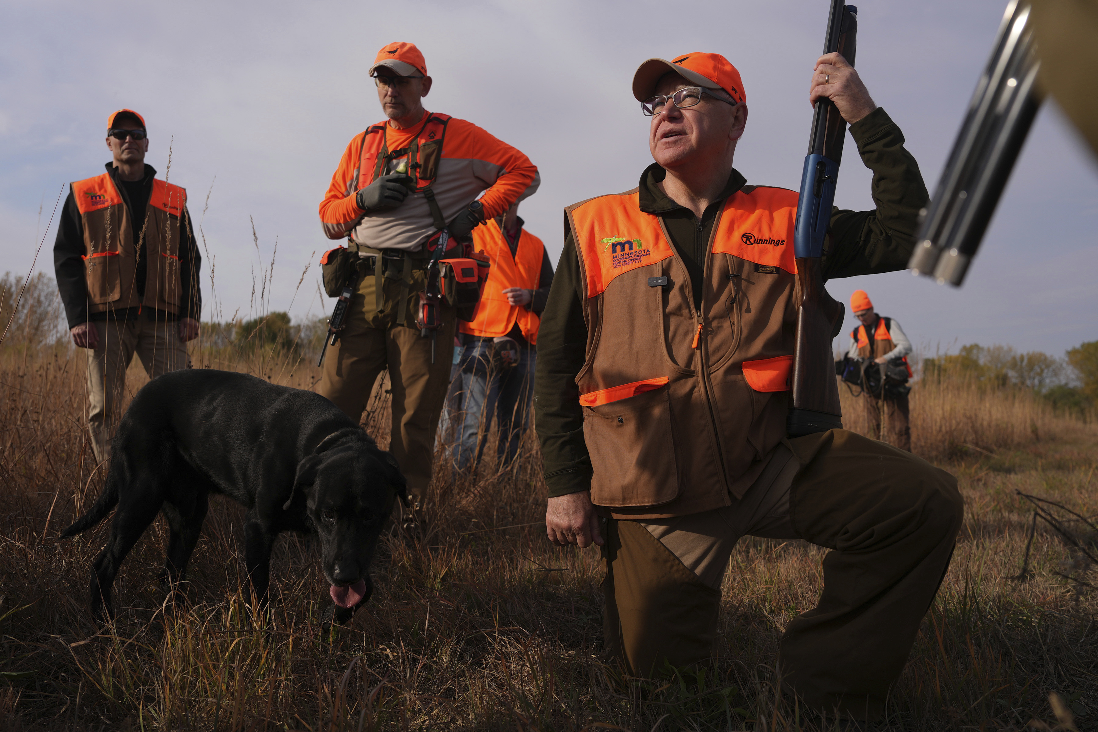 Flanked by his Secret Service detail, Tim Walz, Minnesota governor and Democratic vice presidential candidate, stops during a break to give water to the hunting dogs during the annual Minnesota Governor's Pheasant Hunting Opener near Sleepy Eye, Minn., Saturday, Oct. 12, 2024. (Anthony Souffle/Star Tribune via AP)