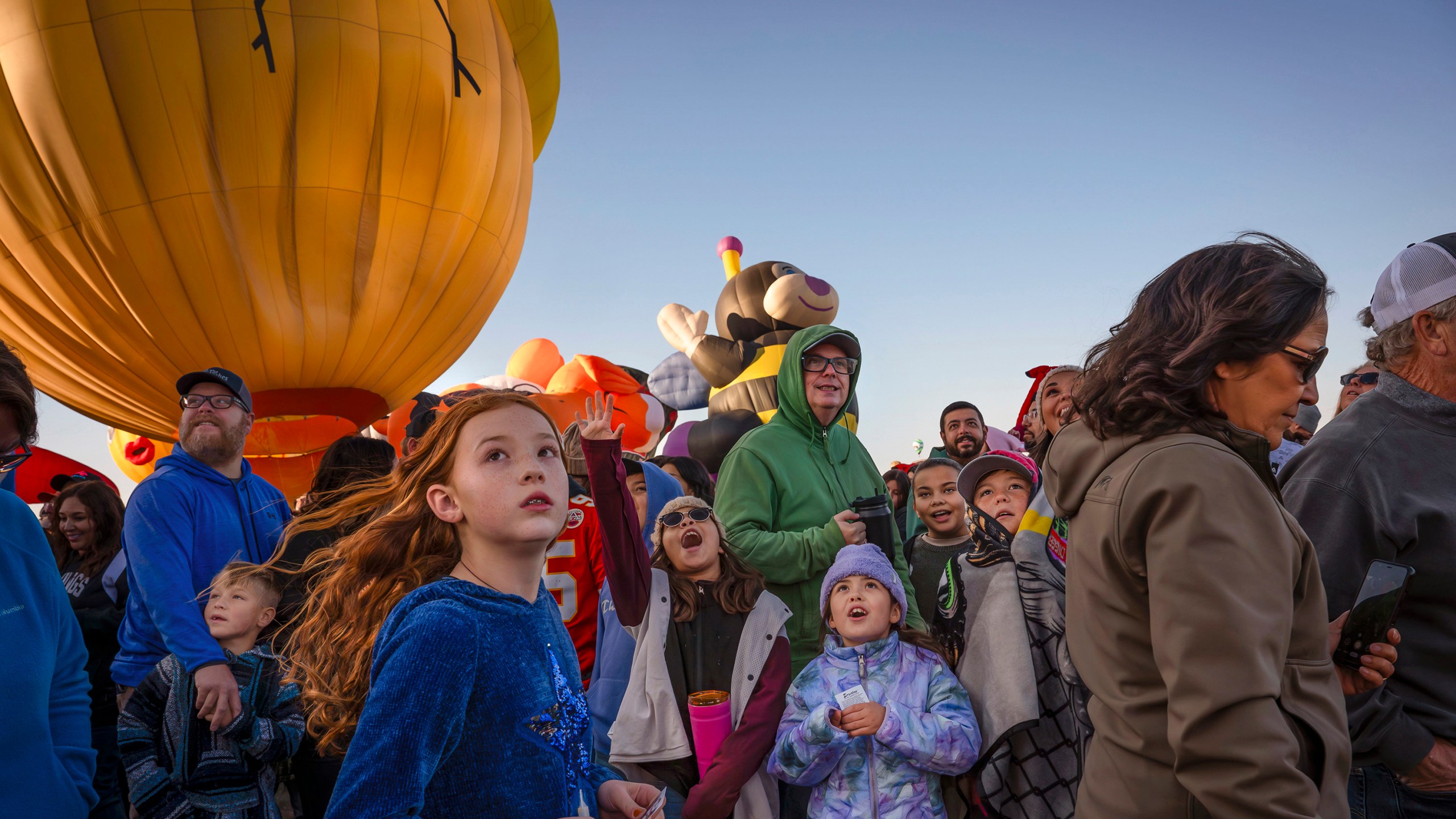 Abiyah Sailors, 9, center left, and Brooklan Parker, 8, center right, react to the Zozobra special shape balloon during the Albuquerque International Balloon Fiesta's Special Shape Rodeo and balloon launch at Balloon Fiesta Park in Albuquerque, N.M., on Thursday, Oct. 10, 2024. (Chancey Bush/The Albuquerque Journal via AP)