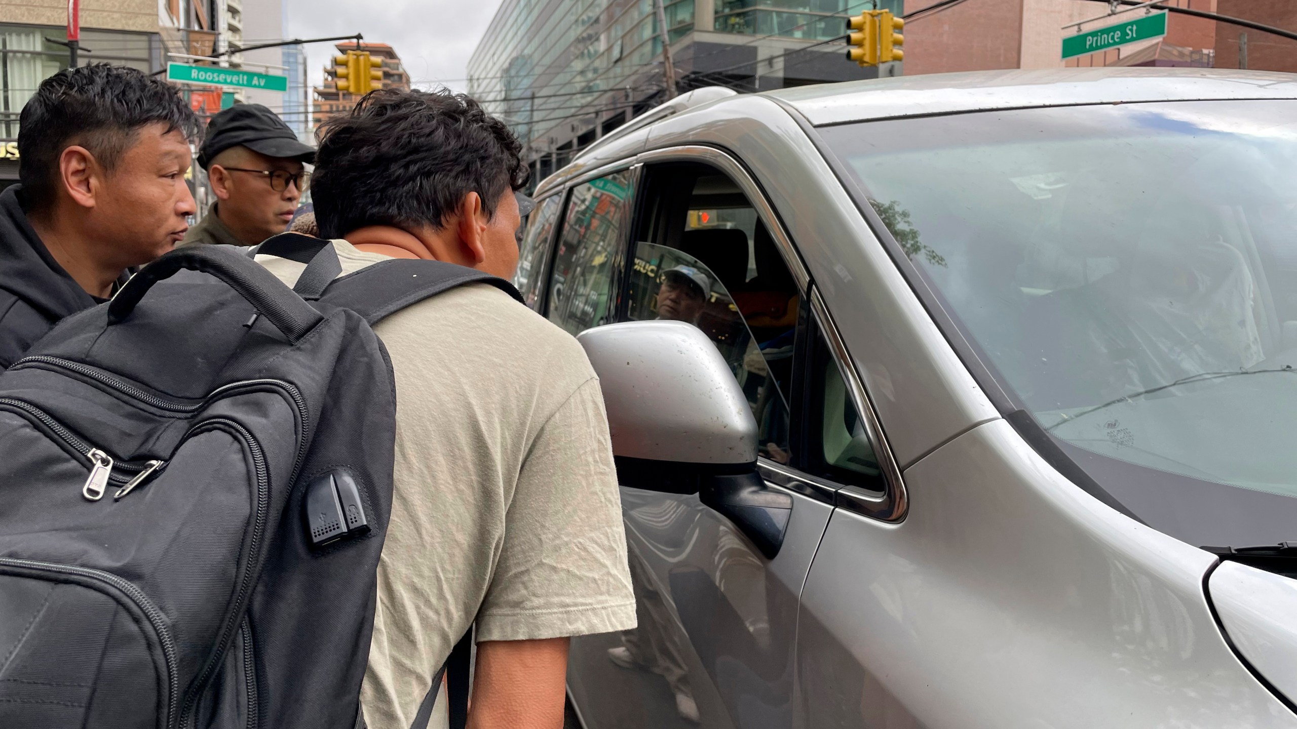 FILE - Wang Gang, 36, front, a Chinese immigrant, talks with the driver of a car with others as they try to get a daily paid job working construction or in another trade in the Flushing neighborhood of the Queens borough of New York on May 3, 2024. (AP Photo/Fu Ting, File)