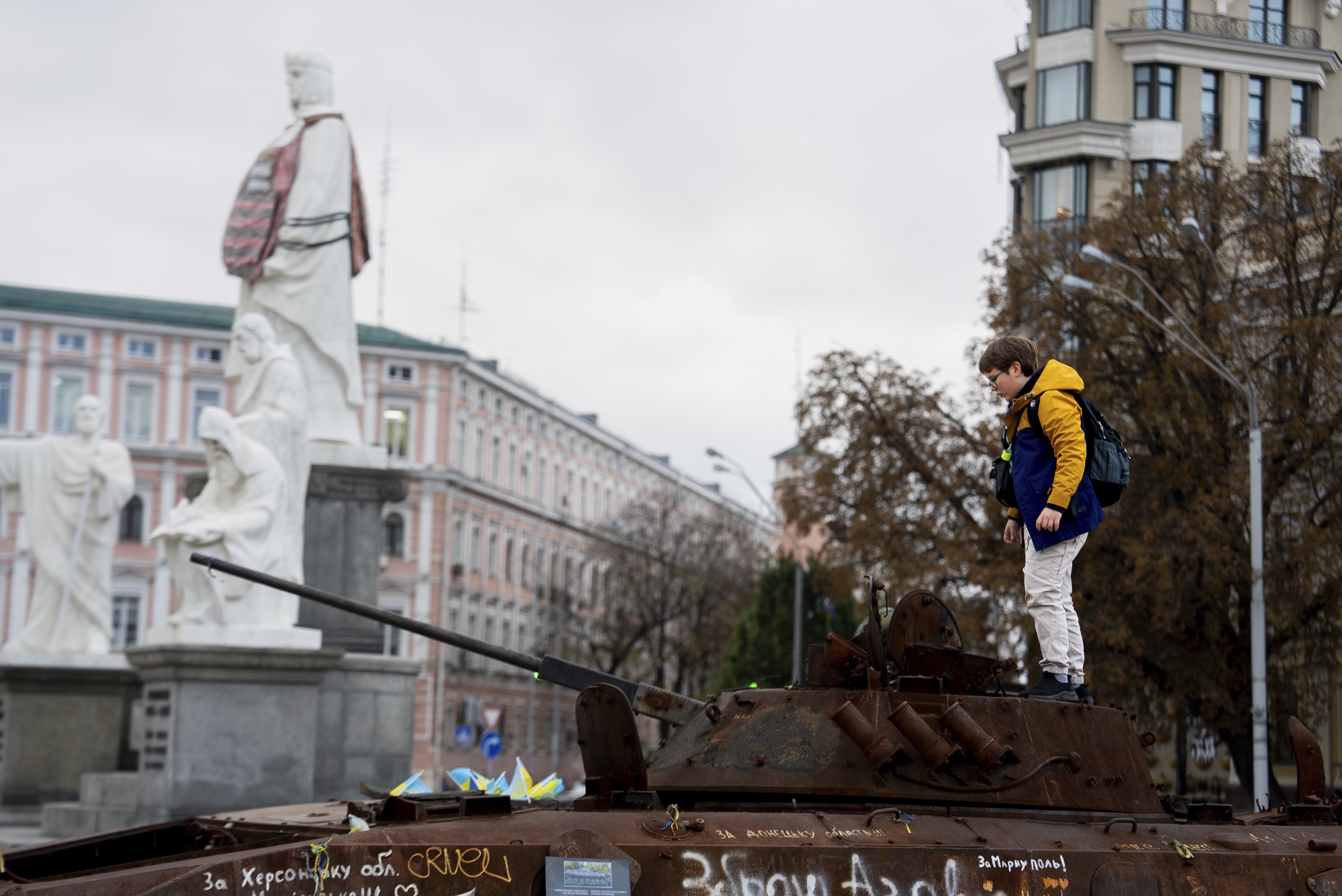 A boy stands on Russian burned APC in central Kyiv, Ukraine, Monday, Oct. 14, 2024. (AP Photo/Alex Babenko)