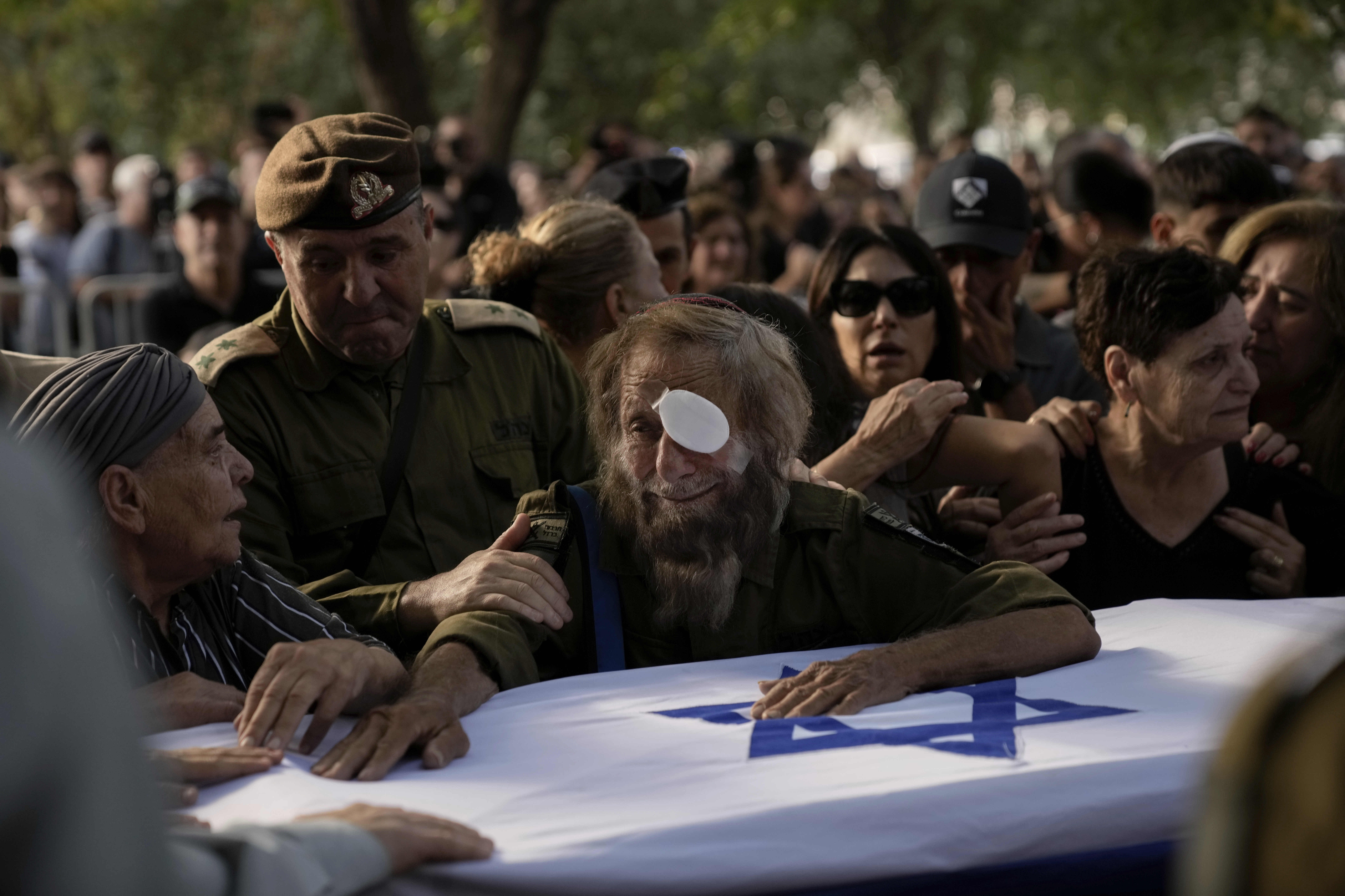 People mourn over the flagged-covered coffin of Israeli soldier Sgt. Amitai Alon, killed by a Hezbollah drone attack, during his funeral near Ramot Naftali, Israel, Monday, Oct. 14, 2024. (AP Photo/Leo Correa)