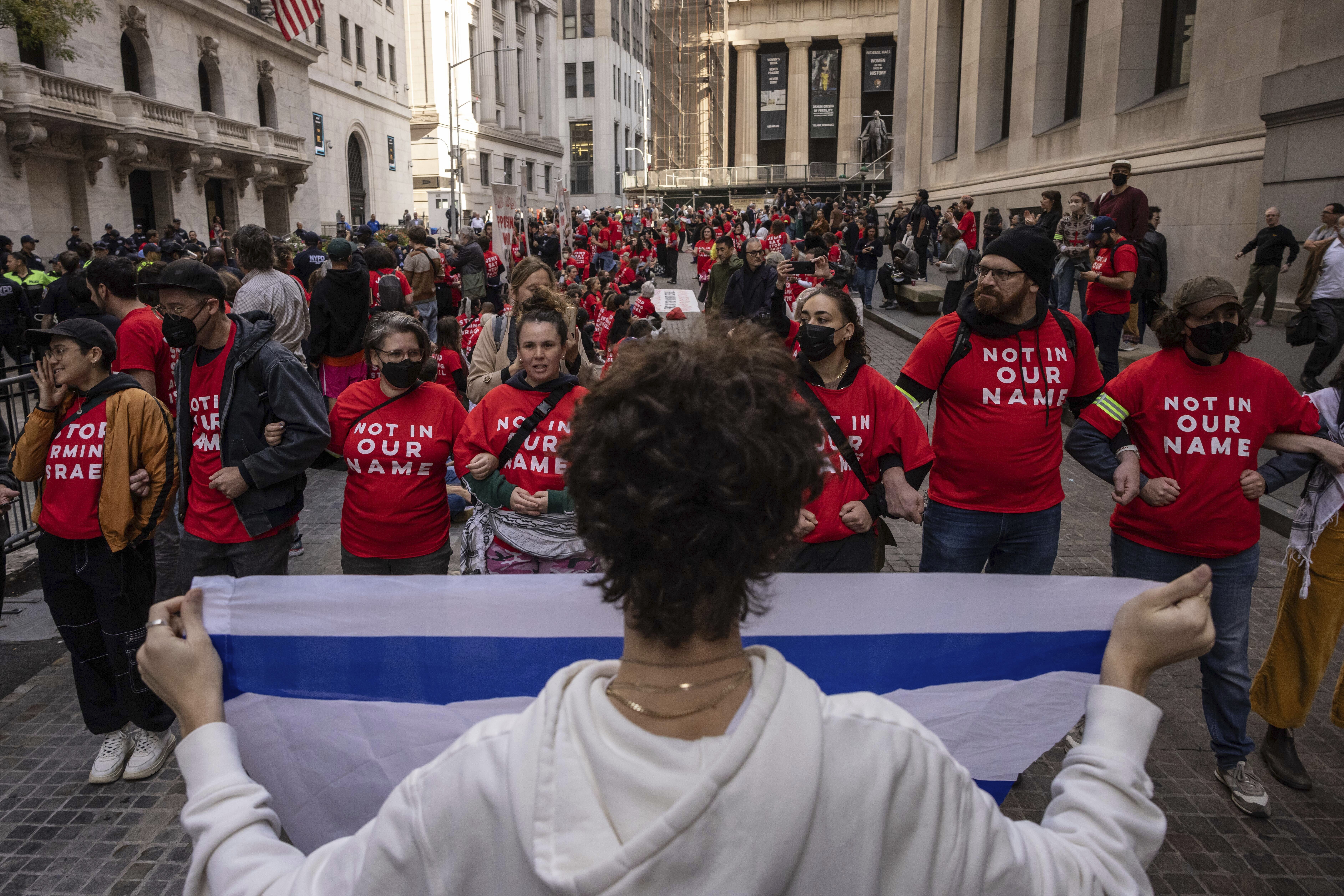 A pro-Israel protester holds an Israeli flag as demonstrators protest Israel's war against Hamas outside the New York Stock Exchange, Monday, Oct. 14, 2024, in New York. (AP Photo/Yuki Iwamura)