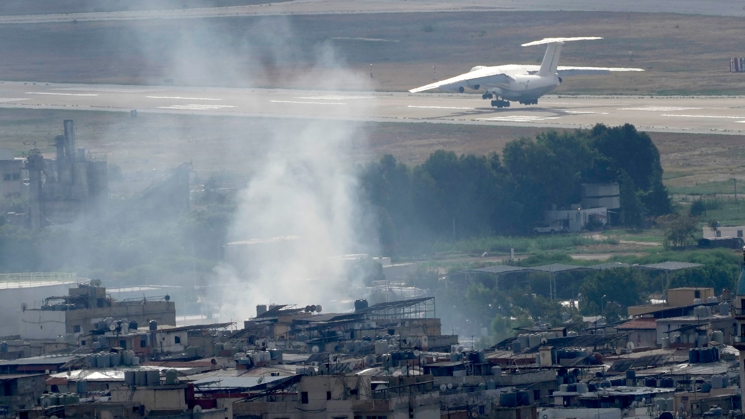 A plane take off from Rafik Hariri international airport as smoke of a past Israeli airstrike still rise from Dahiyeh, in Beirut, Lebanon, Monday, Oct. 14, 2024. (AP Photo/Hussein Malla)