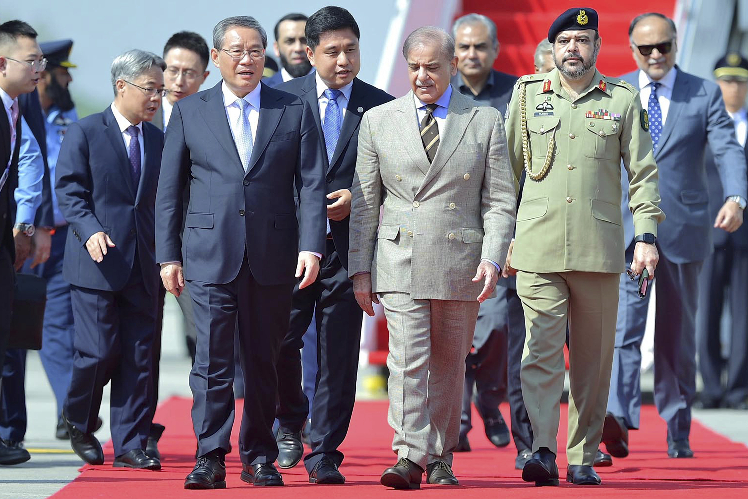 In this photo released by the Press Information Department, China's Premier Li Qiang, third left, walks Pakistan's Prime Minister Shehbaz Sharif, third right, upon his arrival at an airbase in Rawalpindi, Pakistan, Monday, Oct. 14, 2024. (Press Information Department via AP)