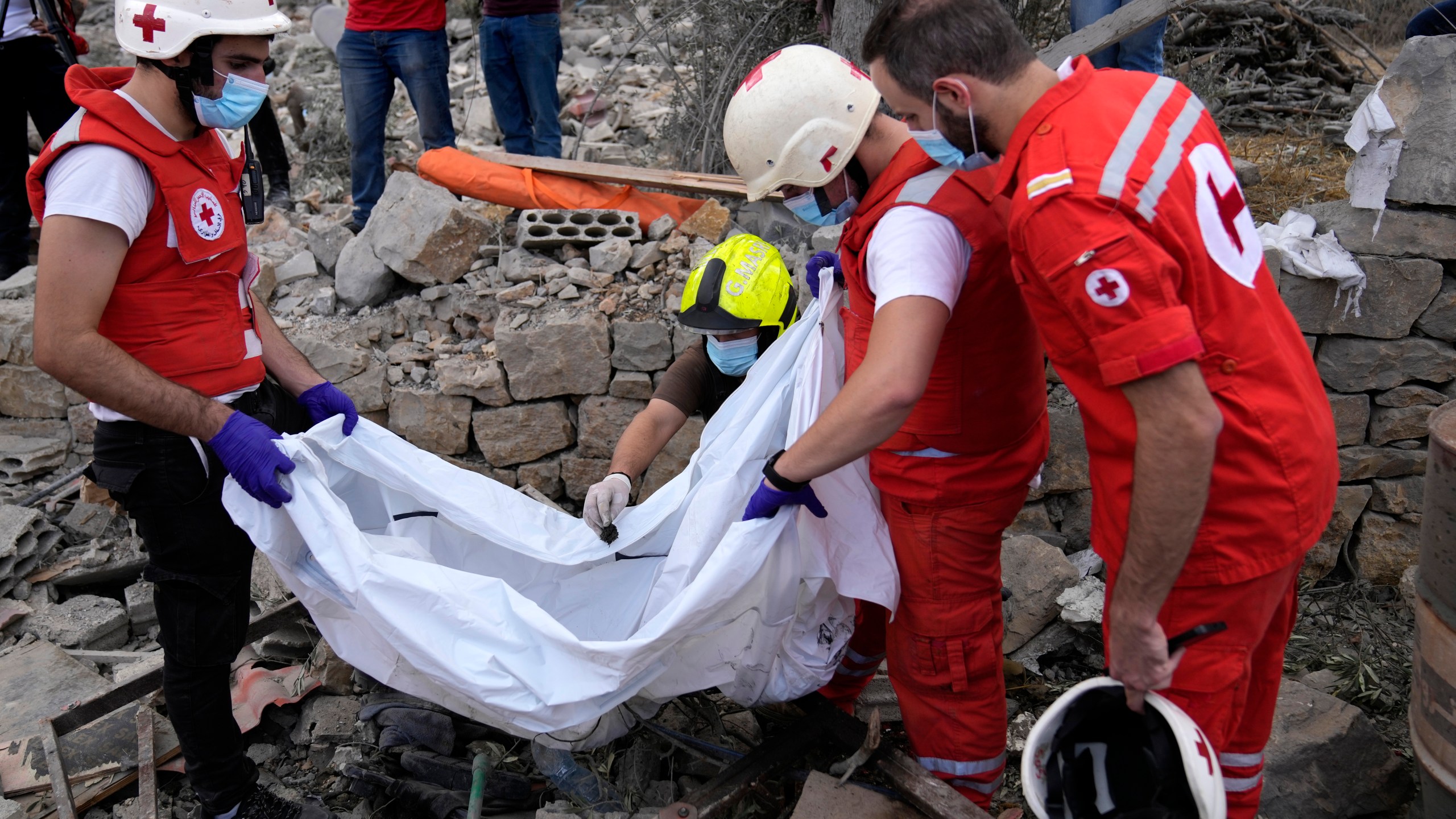 Lebanese Red Cross volunteers remove the remains of killed people from the rubble of a destroyed building at the site of Monday's Israeli airstrike in Aito village, north Lebanon, Tuesday, Oct. 15, 2024. (AP Photo/Hussein Malla)