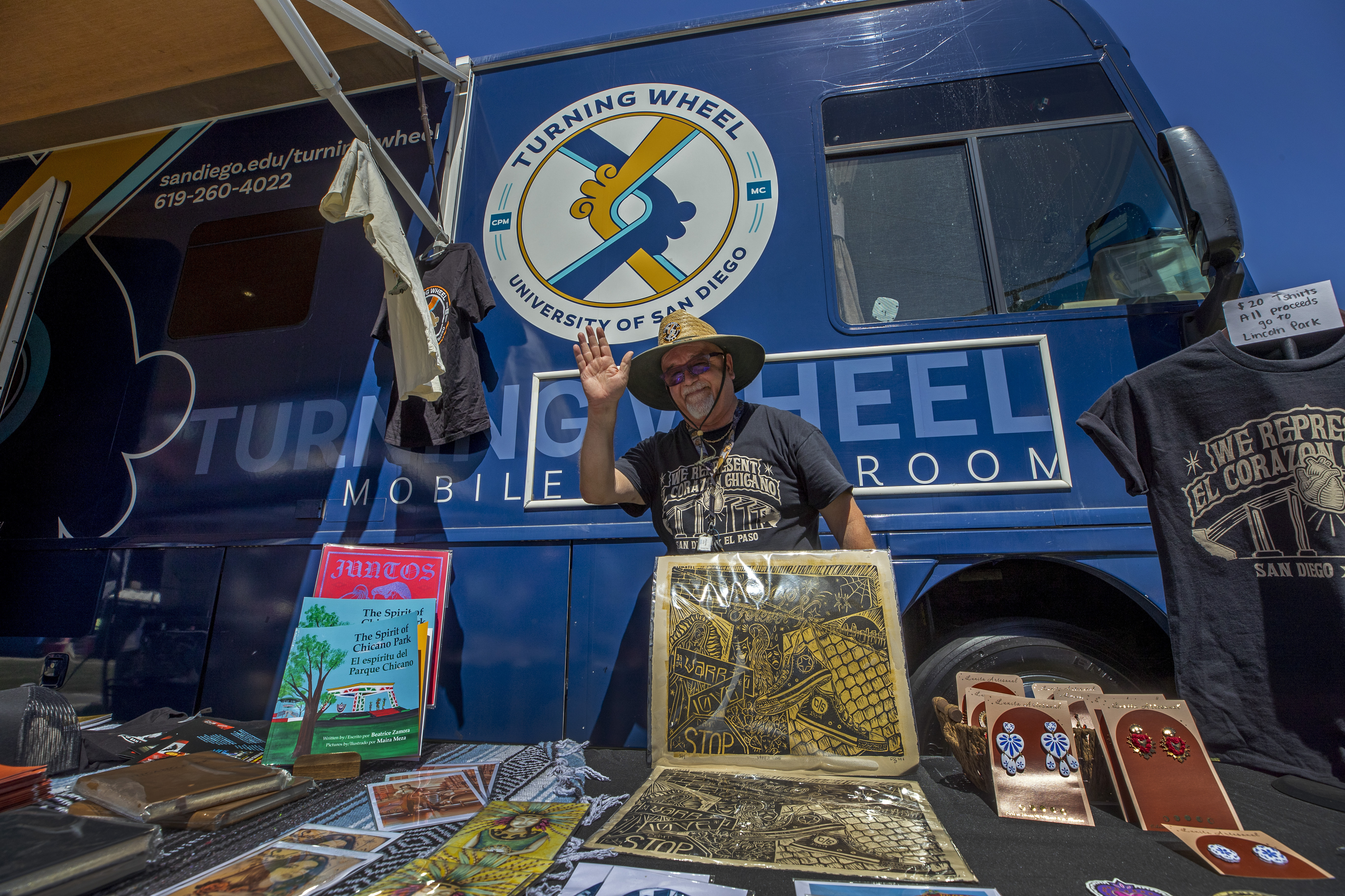 University of San Diego professor Alberto Lopez Pulido waves from his mobile classroom bus while attending a lowrider exhibition for the 20th anniversary of Lincoln Park in El Paso, Texas, Sunday, Sept. 22, 2024. (AP Photo/Andrés Leighton)