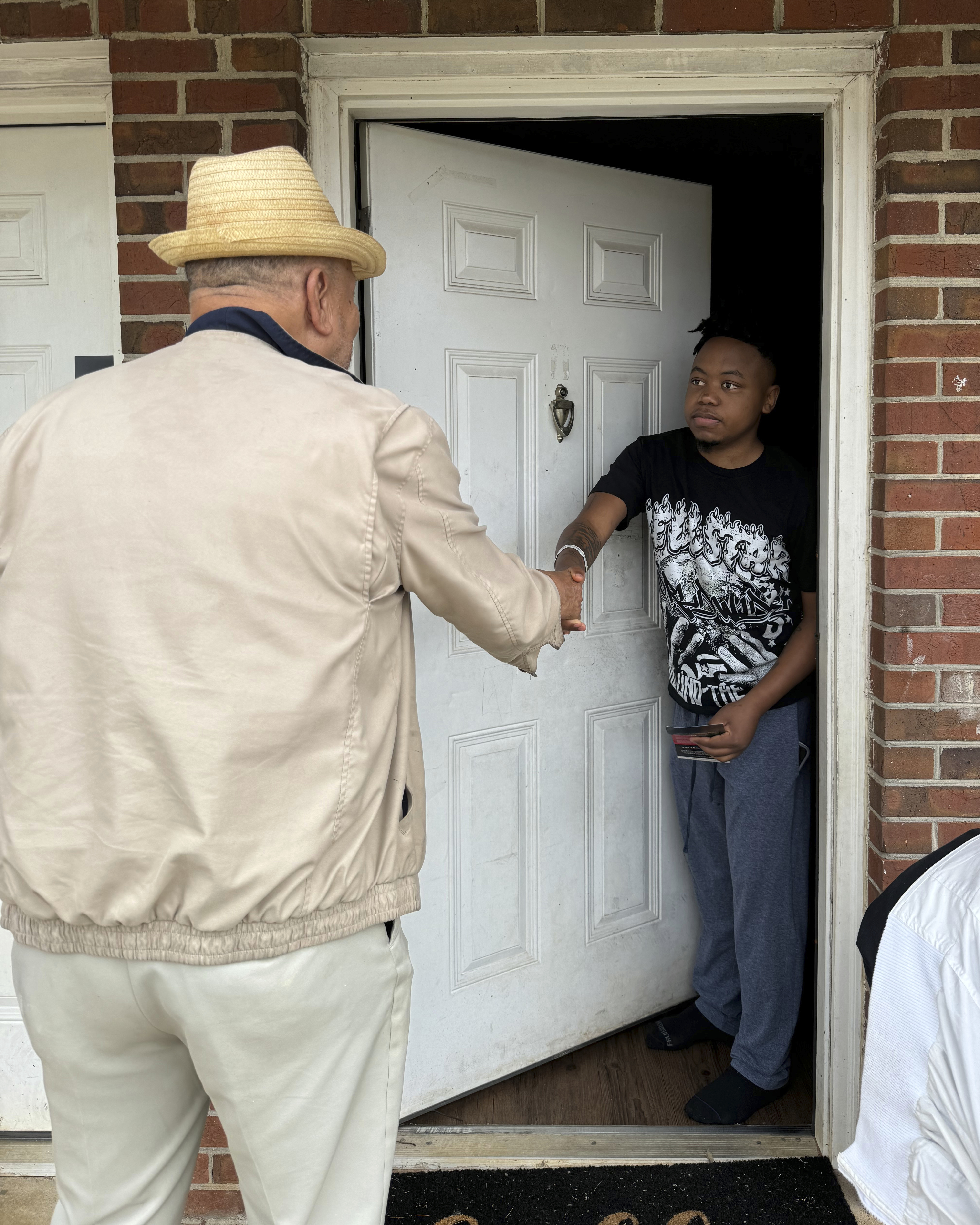 The Rev. Ezekiel Holley shakes hands with Jaleen Green in Terrell County and asks him if he is registered to vote in Georgia's Terrell County on Oct. 5, 2024. (AP Photo/Charlotte Kramon)