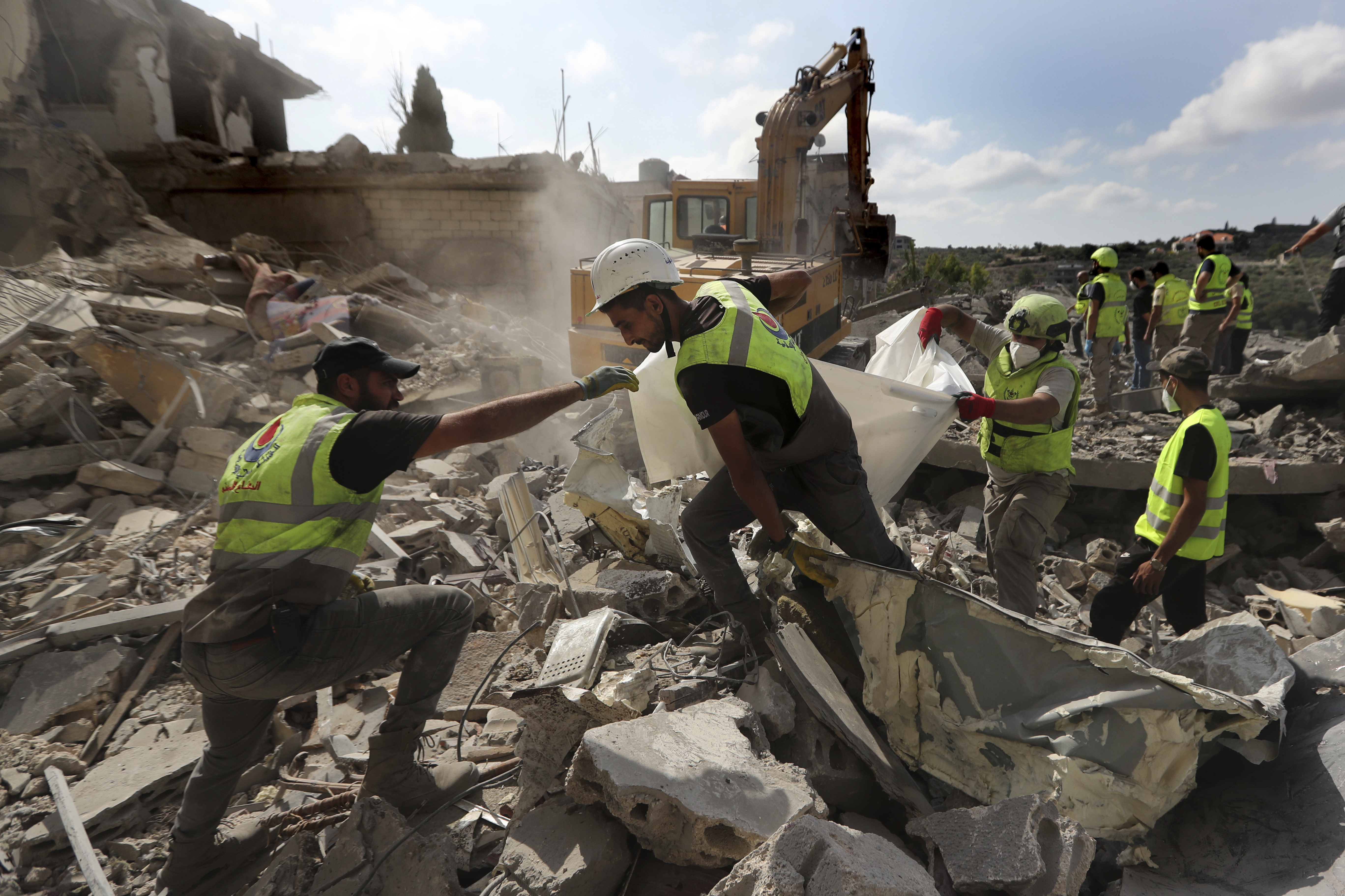 Rescue workers carry remains of people at at site that was hit by Israeli airstrikes in Qana village, south Lebanon, Wednesday, Oct. 16, 2024. (AP Photo/Mohammed Zaatari)