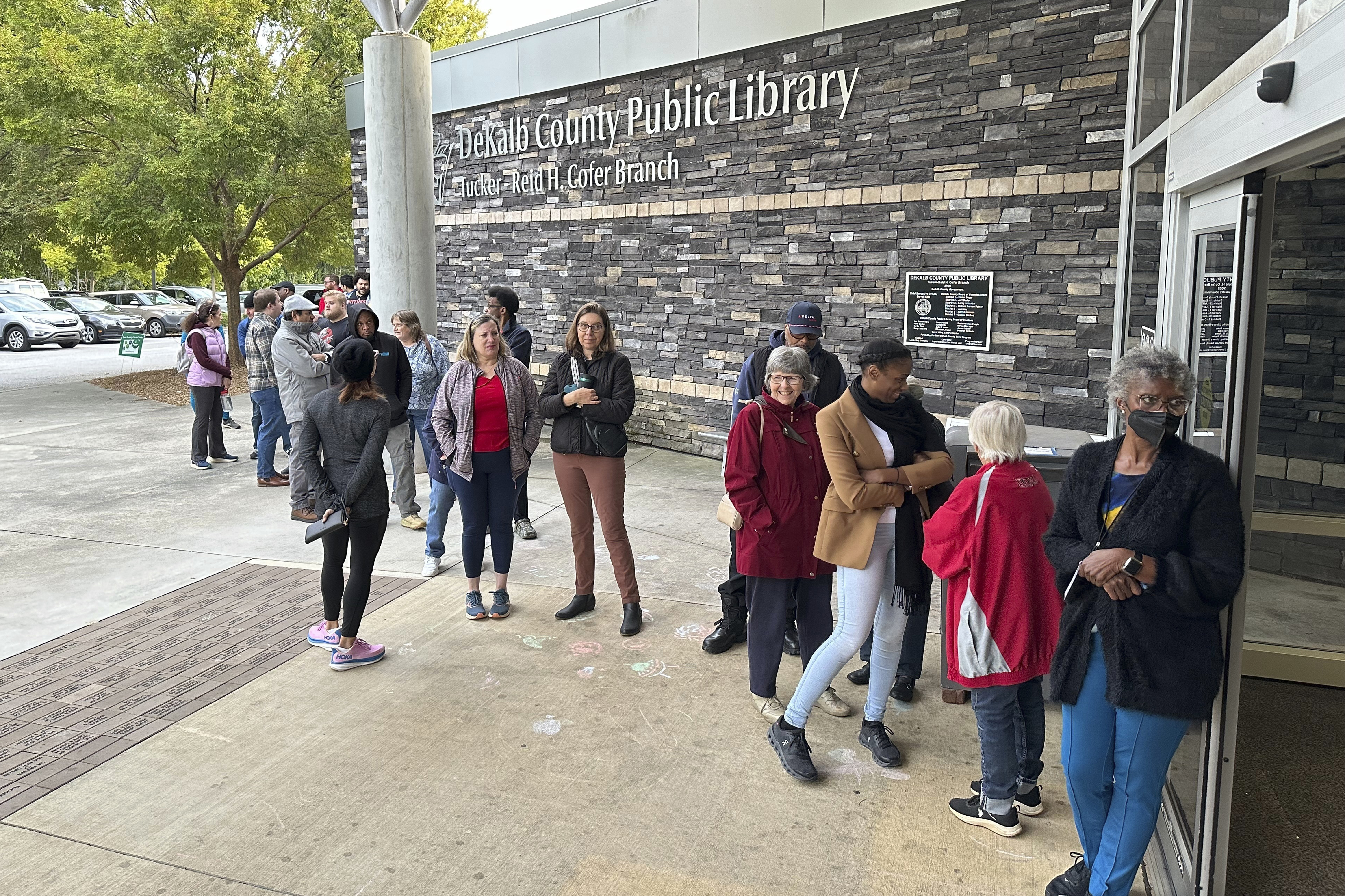 People line up to vote in the Atlanta suburb of Tucker, Ga., on Tuesday, Oct. 15, 2024, the first day of early in-person voting in Georgia. (AP Photo/Jeff Amy)