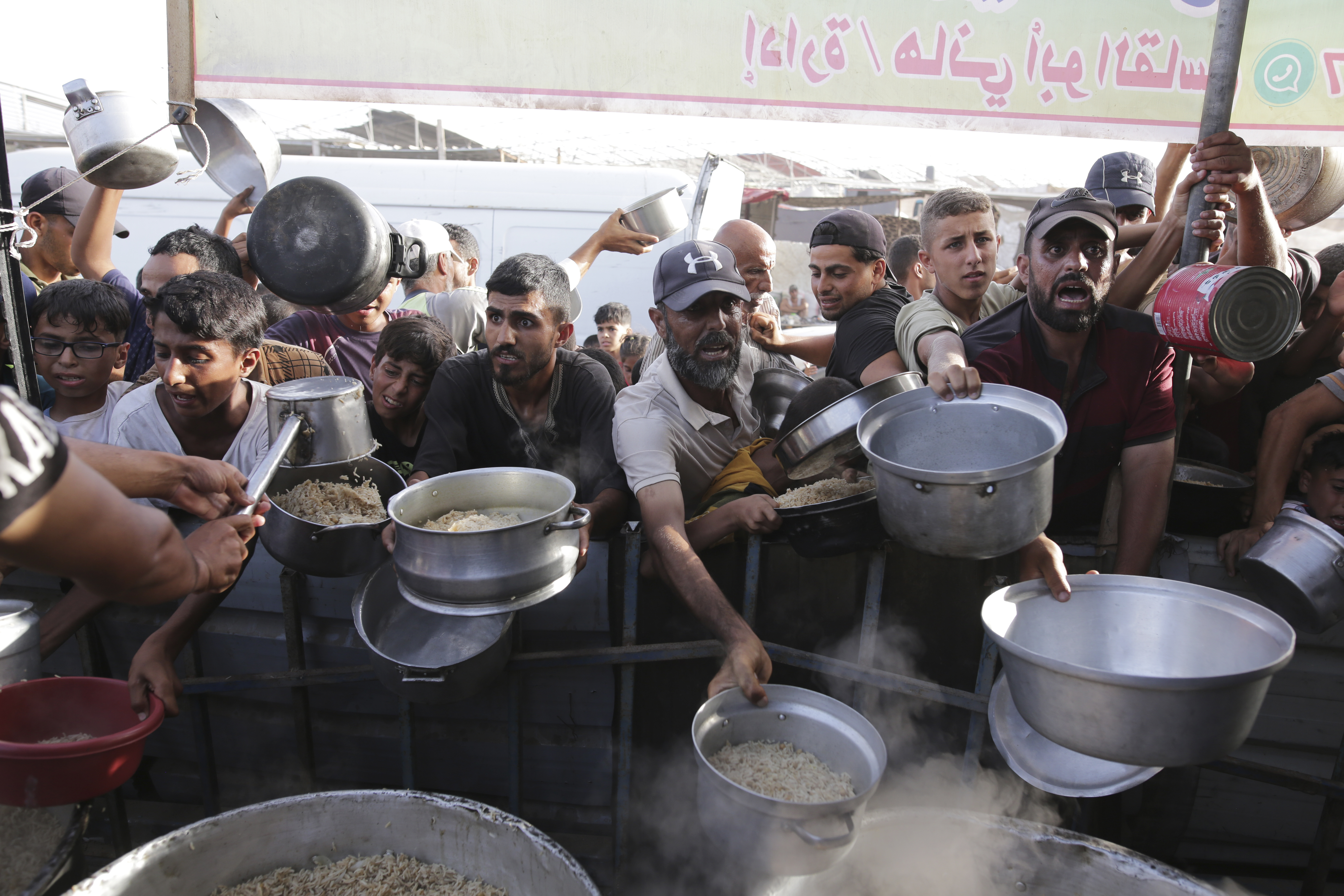 FILE - Palestinian men collect food aid ahead of the upcoming Eid al-Adha holiday in Khan Younis, Gaza Strip, on June 15, 2024. (AP Photo/Jehad Alshrafi, File)