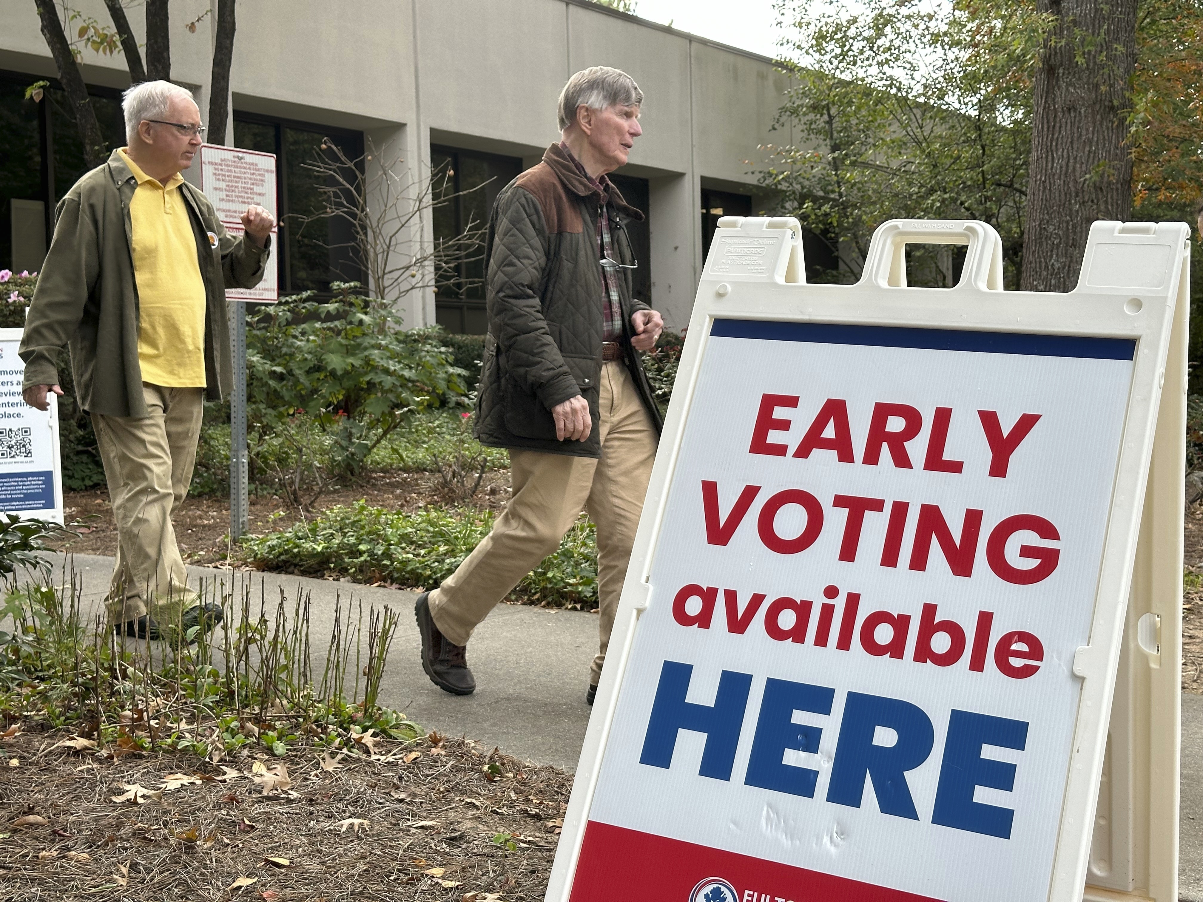 People leave after voting in the Atlanta suburb of Sandy Springs, Ga., on Tuesday, Oct. 15, 2024, the first day of early in-person voting in Georgia. (AP Photo/Jeff Amy)