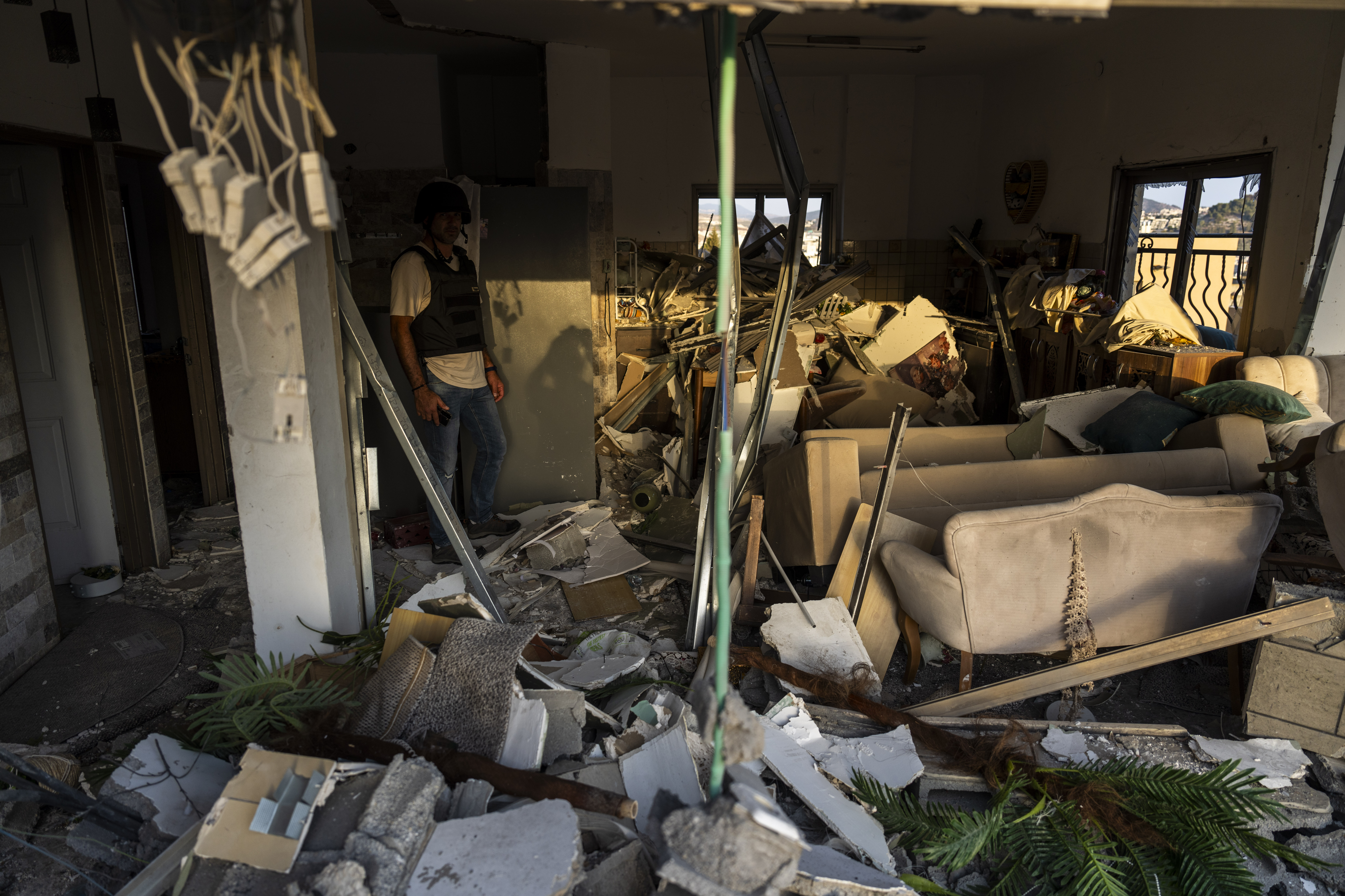 An Israeli security forces officer examines the damage to a home struck by a rocket fired from Lebanon in the town of Majd al-Krum, northern Israel, Wednesday, Oct. 16, 2024. (AP Photo/Ariel Schalit)