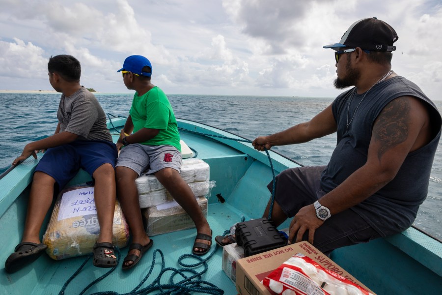 Metfidza Marino, from left, Aarson Aaron and Aaron Cyrillo look out to Helen Island, Palau, as a small speed boat transports toilet paper, dog food and other goods to the remote atoll on July 17, 2024. (AP Photo/Yannick Peterhans)