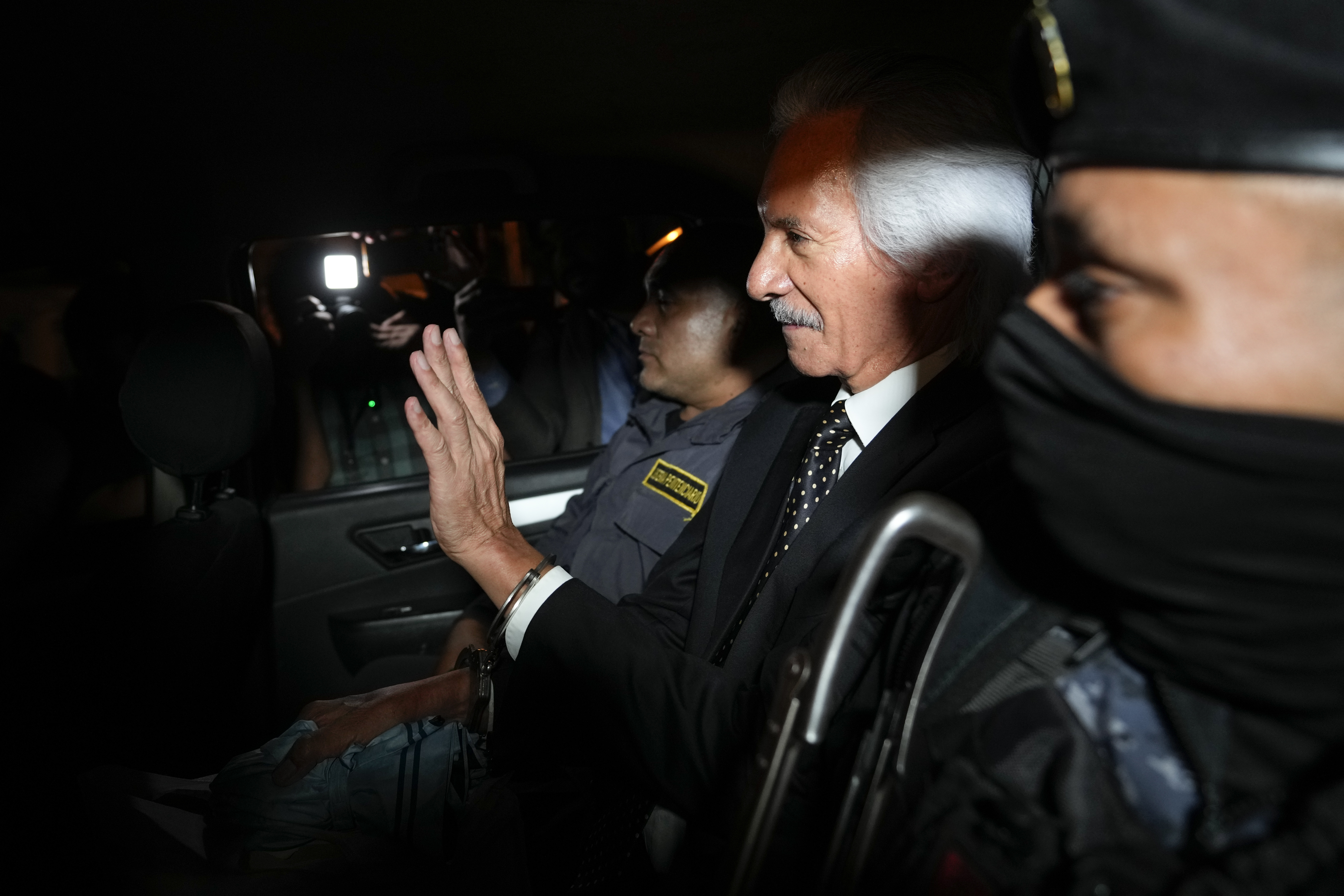 Guatemalan journalist Jose Ruben Zamora, founder of El Periodico newspaper, jailed for more than two years on money laundering charges, waves from inside a police car after a judge granted him house arrest, in Guatemala City, Friday, Oct. 18, 2024. (AP Photo/Moises Castillo)