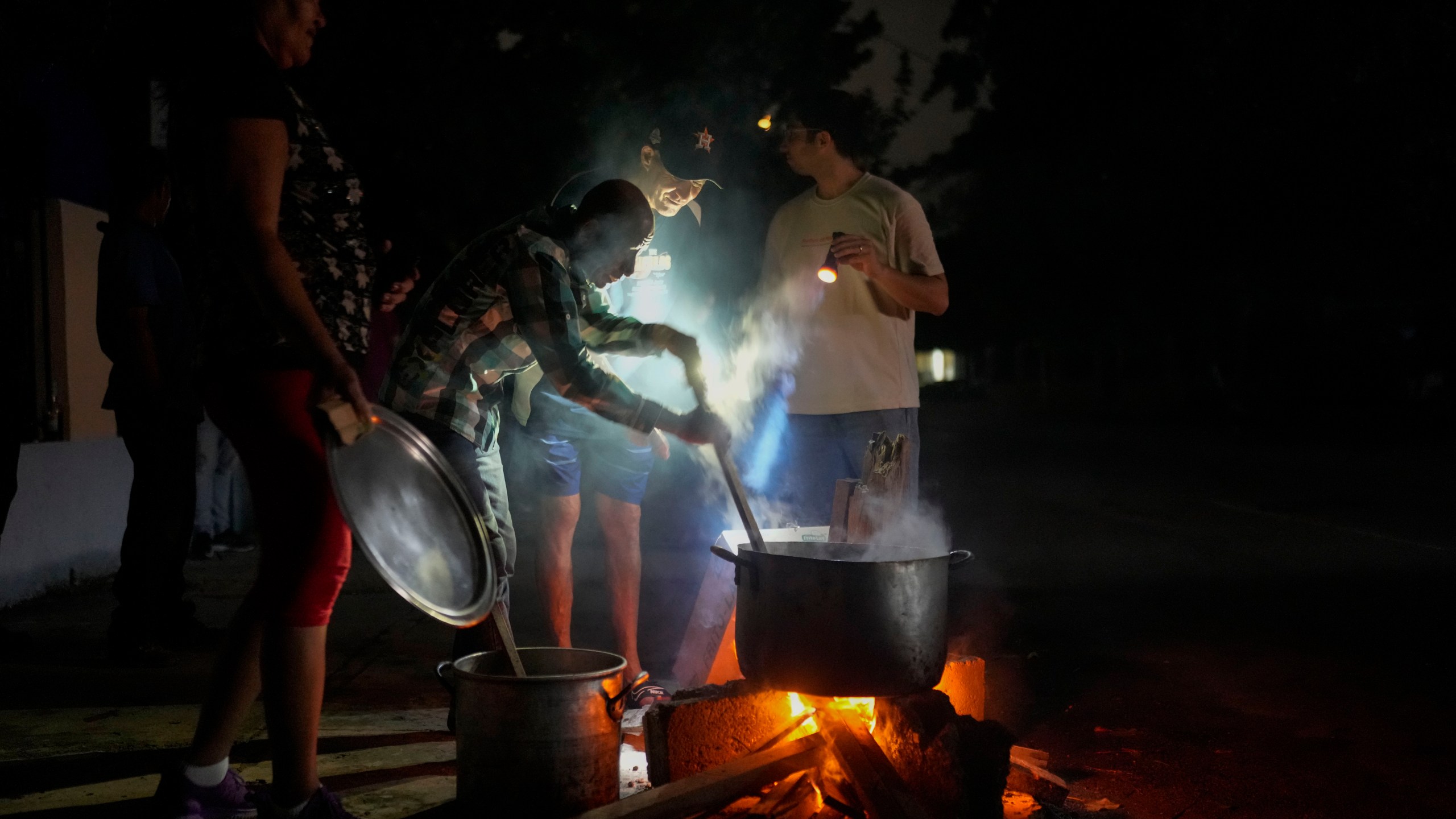 Residents prepare a soup over an open fire during a blackout following the failure of a major power plant in Havana, Cuba, Saturday, Oct. 19, 2024. (AP Photo/Ramon Espinosa)