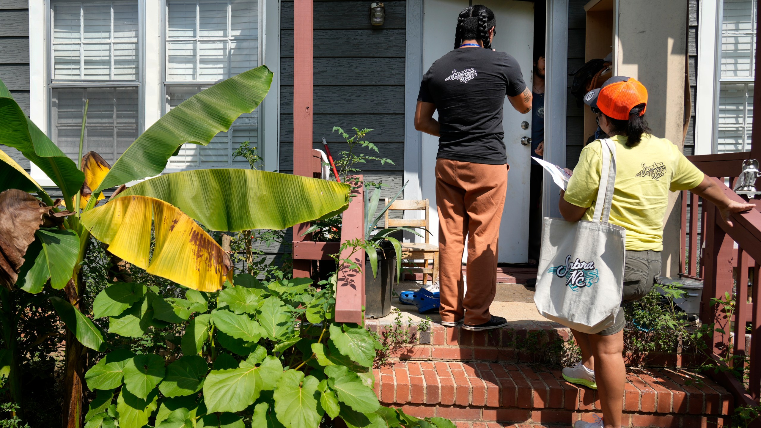 Salvador Fonseca, left, and Elena Jimenez talk to a homeowner during a voter engagement event for the Latino community in Greensboro, N.C., Saturday, Sept. 21, 2024. (AP Photo/Chuck Burton)