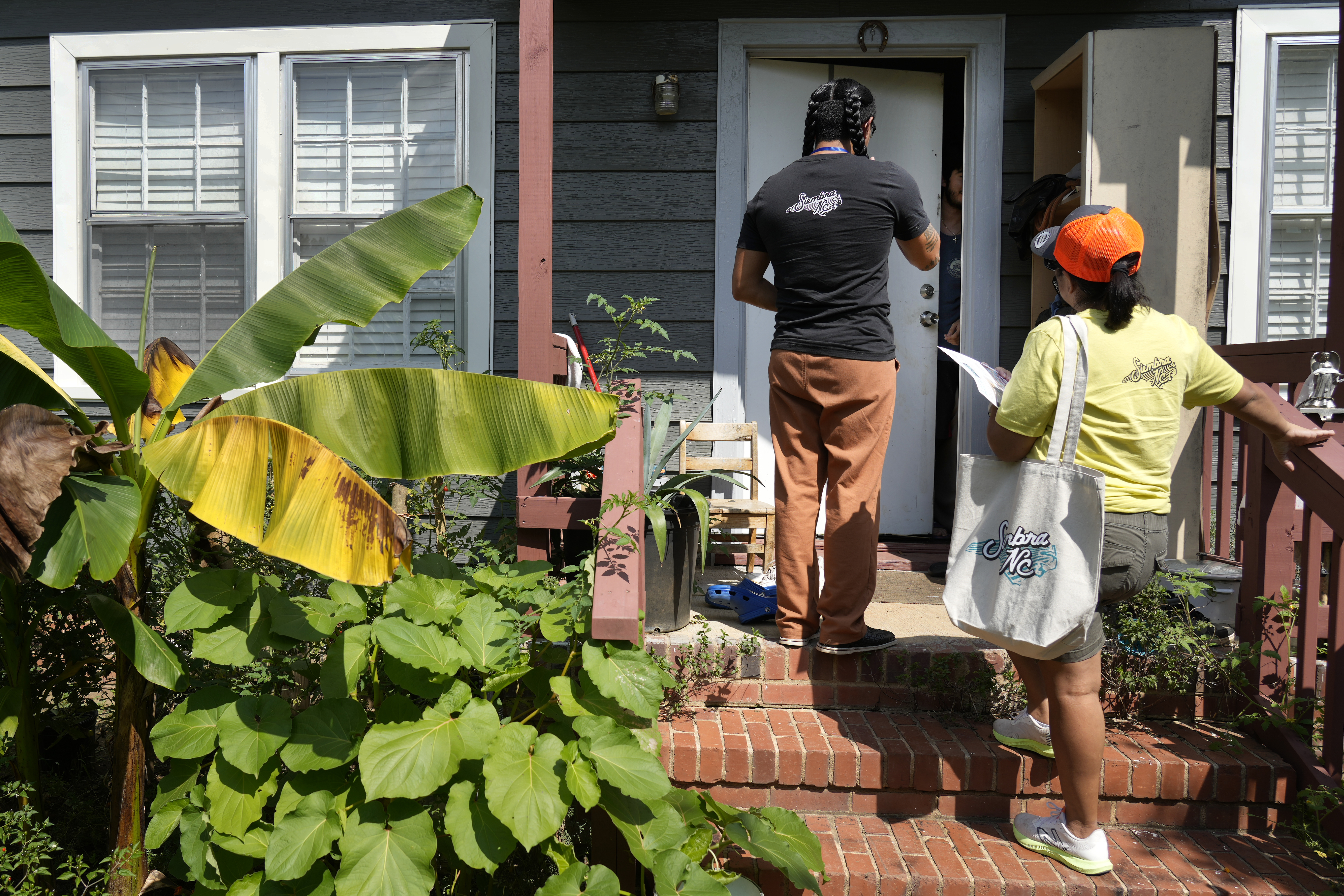 Salvador Fonseca, left, and Elena Jimenez talk to a homeowner during a voter engagement event for the Latino community in Greensboro, N.C., Saturday, Sept. 21, 2024. (AP Photo/Chuck Burton)