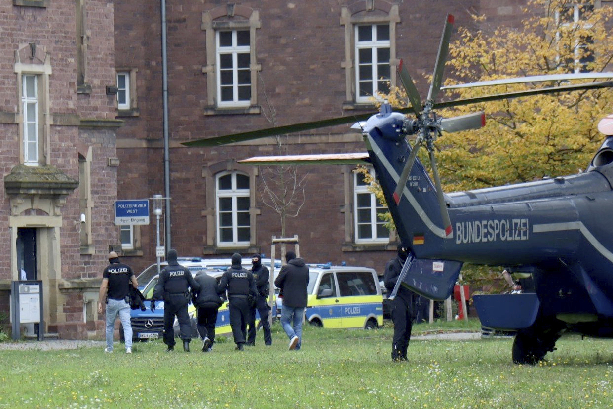 Police officers escort a Libyan national with suspected ties to the extremist group Islamic State who was allegedly planning an attack on the Israeli Embassy in Berlin, in Karlsruhe, Germany, Sunday Oct. 20, 2024. (Rene Priebe/dpa via AP)