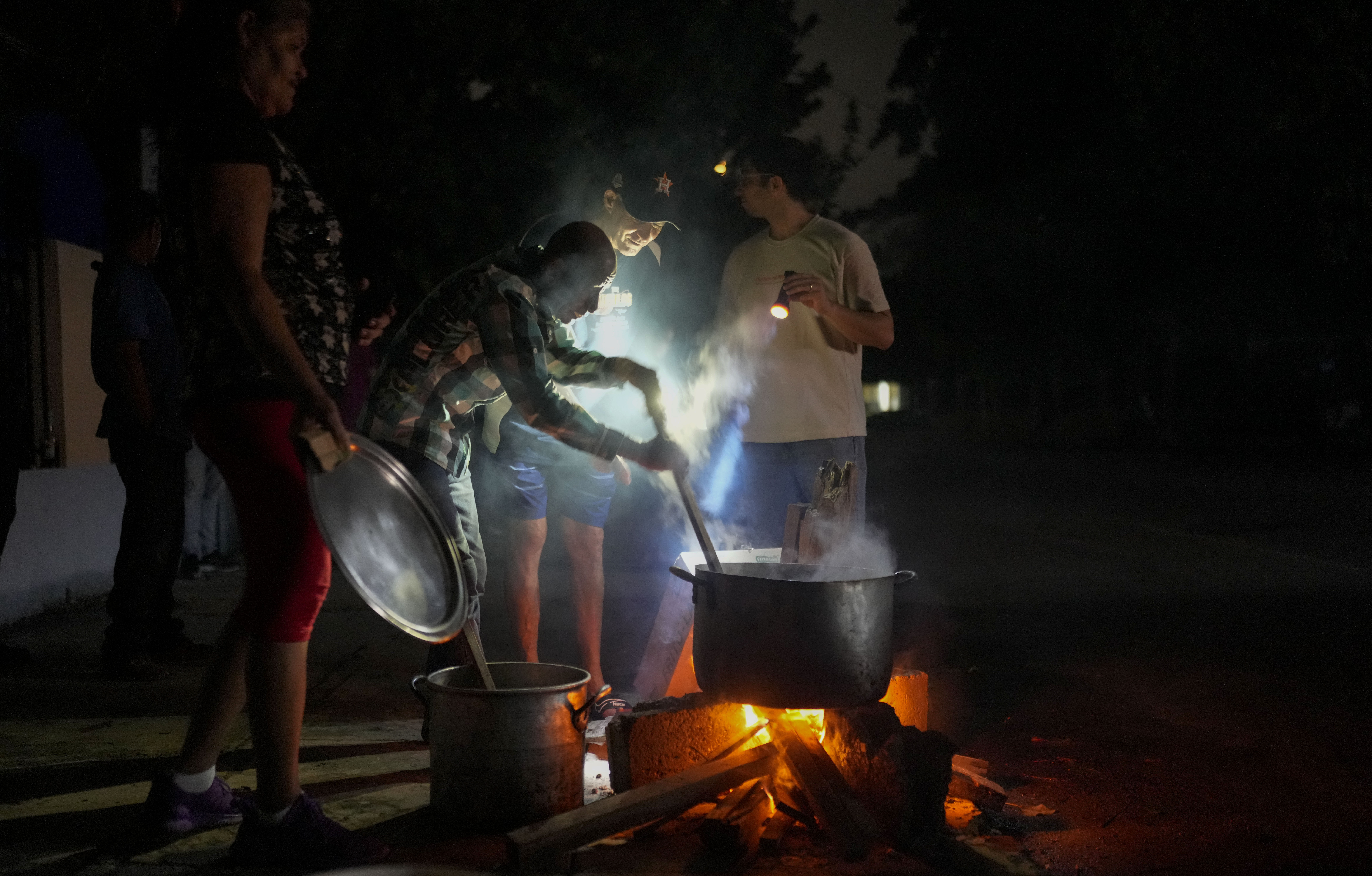 Residents prepare a soup over an open fire during a blackout following the failure of a major power plant in Havana, Cuba, Saturday, Oct. 19, 2024. (AP Photo/Ramon Espinosa)