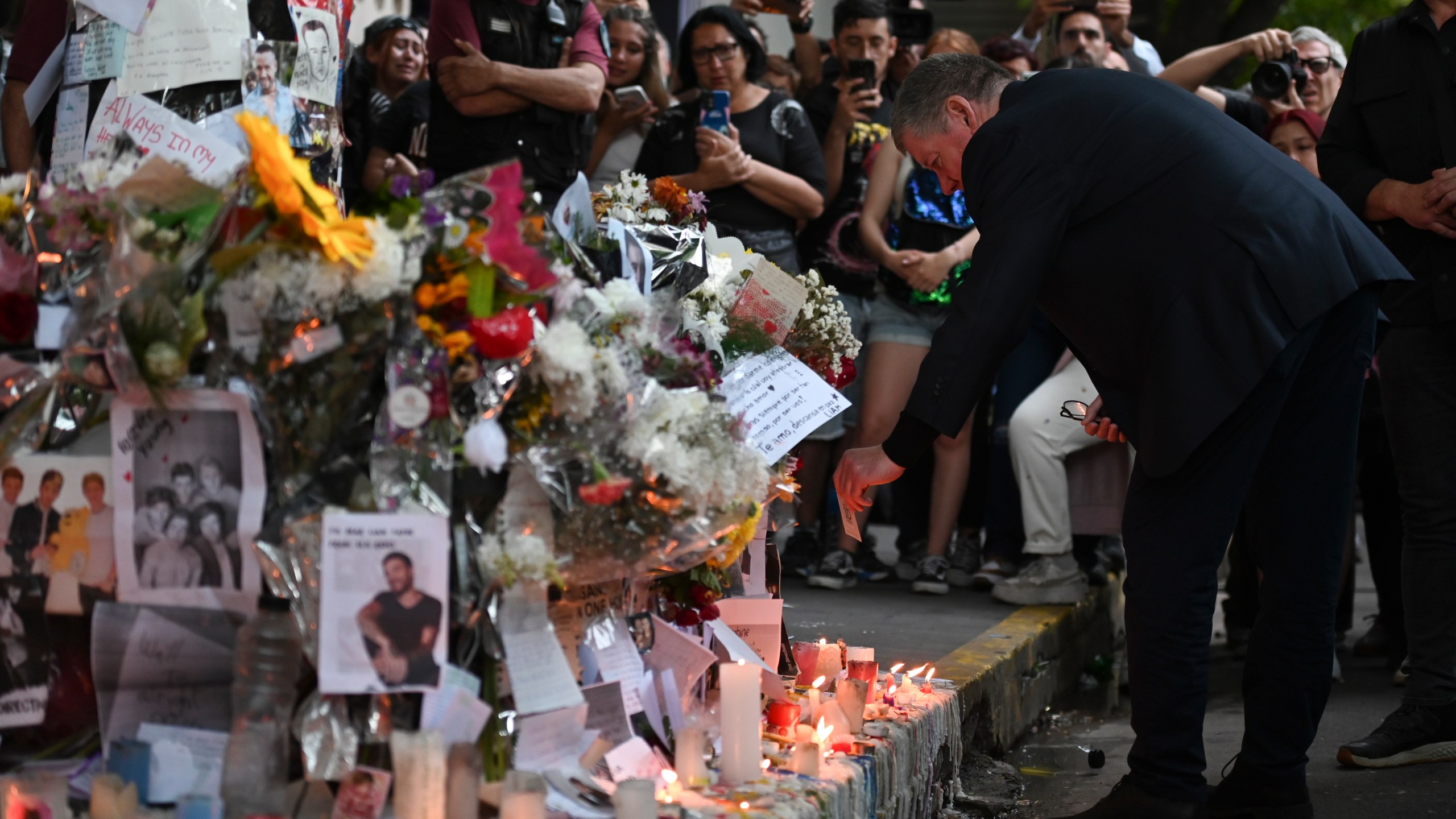 Geoff Payne, a la derecha, padre del exintegrante de One Direction, el cantante Liam Payne, visita un altar improvisado fuera del hotel Casa Sur Hotel donde el artista pop británico murió al precipitarse desde un balcón, en Buenos Aires, Argentina, el viernes 18 de octubre de 2024. (AP Foto/Mario de Fina)