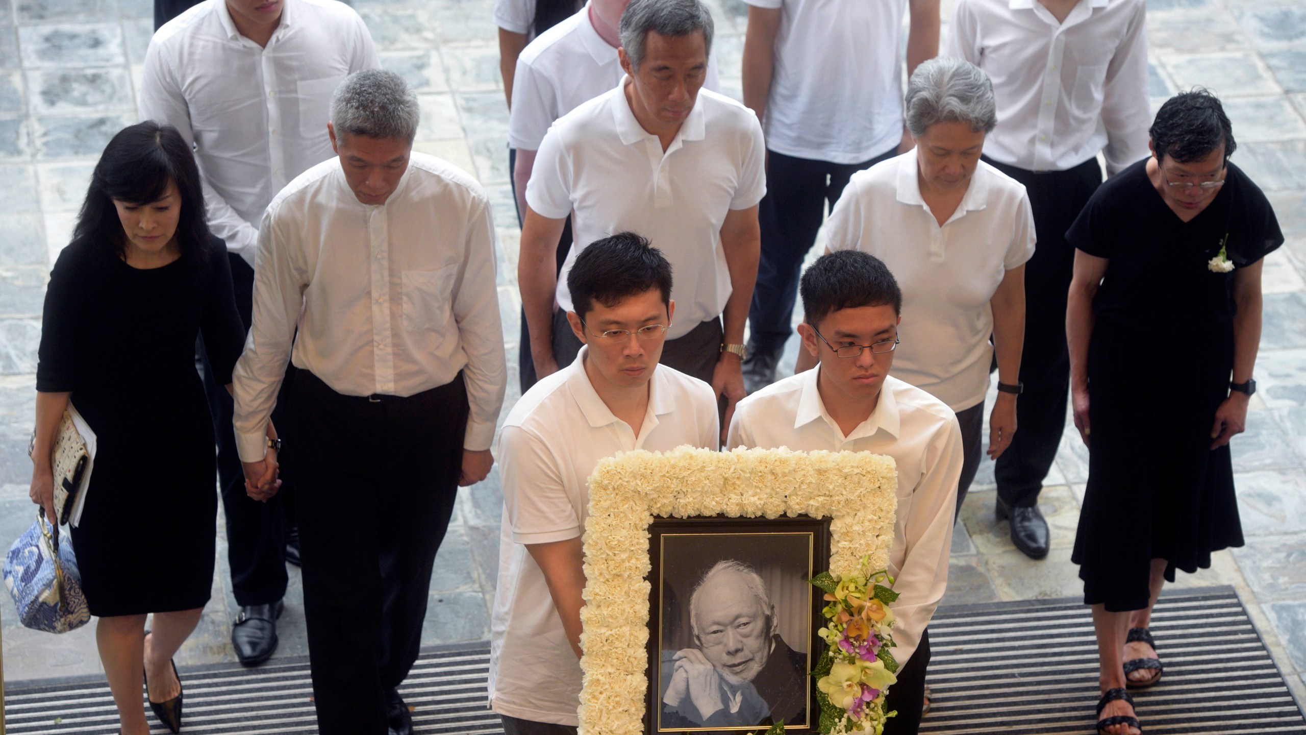 FILE - Family members, second row left to right, Lee Suet Fern, son, (Lee Hsien Yang's wife), Lee Hsien Yang, Lee Hsien Loong, son and current prime minister, Ho Ching (Lee Hsien Loong's wife) and Lee Wei Ling, daughter, of the late Lee Kuan Yew arrive with his portrait at the start of the state funeral at the University Cultural Center in Singapore, Sunday, March 29, 2015. (AP Photo/Joseph Nair, File)