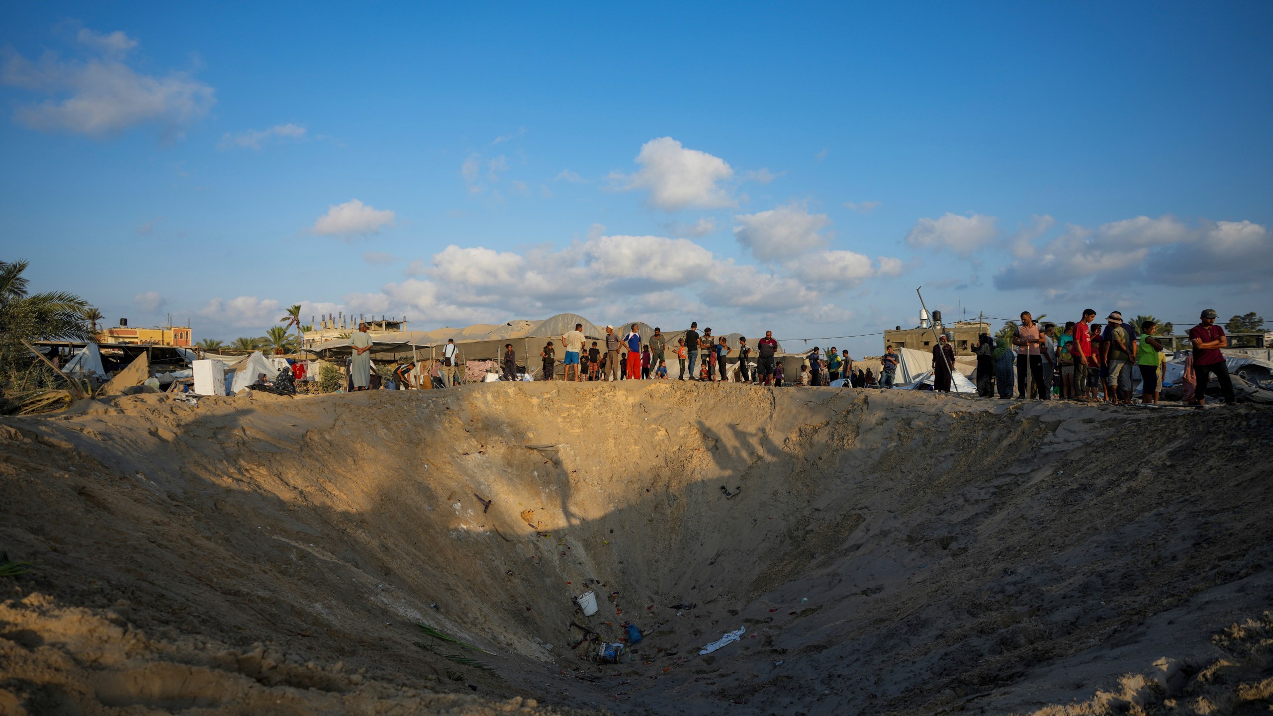 FILE - Palestinians look at the destruction after an Israeli airstrike on a crowded tent camp housing Palestinians displaced by the war in Muwasi, Gaza Strip, on Sept. 10, 2024. (AP Photo/Abdel Kareem Hana, File)