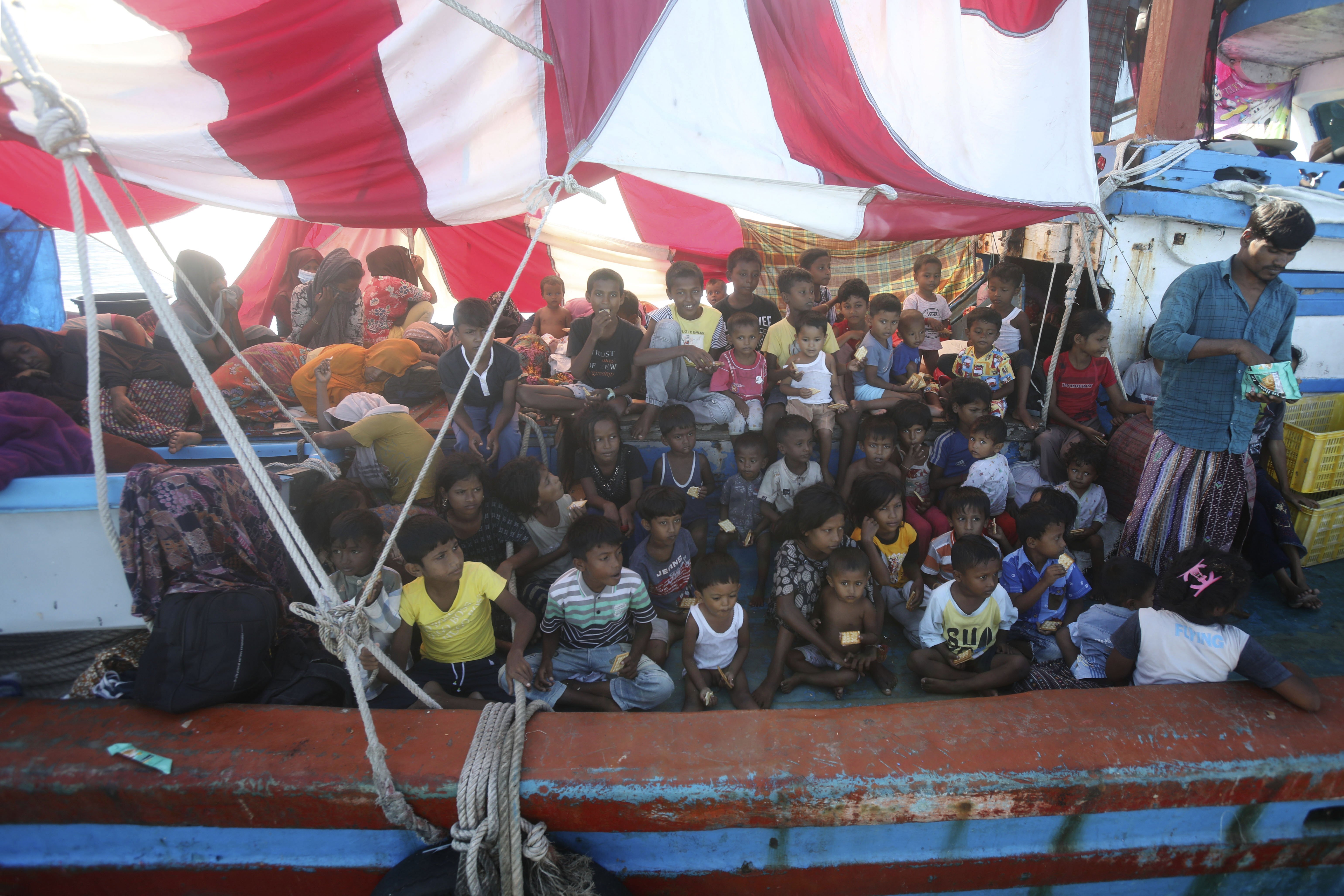 Rohingya children wait for food supply delivered by local fishermen on their boat anchored in the waters near the coast of Labuhan Haji, Aceh province, Indonesia, Tuesday, Oct. 22, 2024. (AP Photo/Binsar Bakkara)