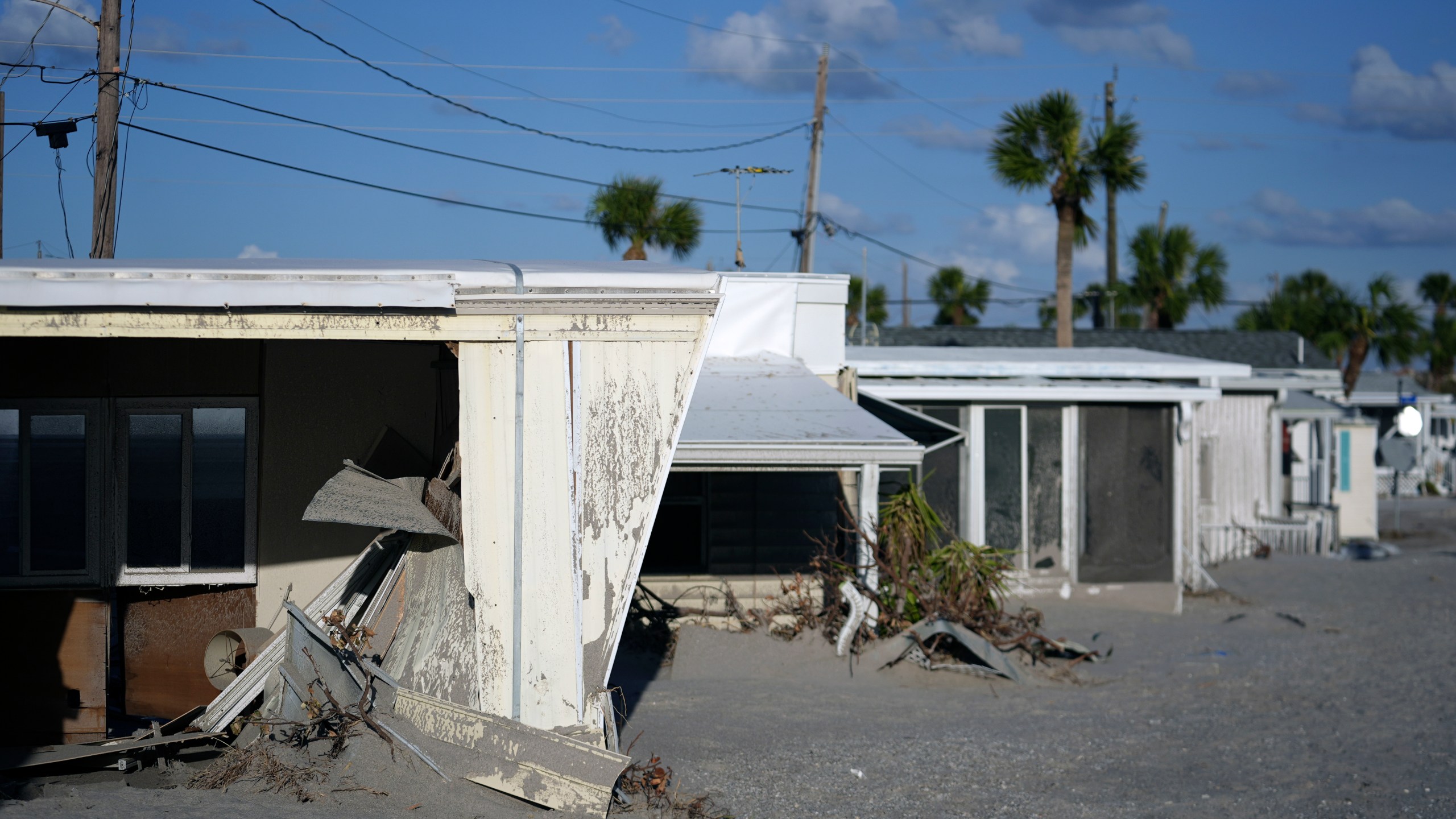 Trailers are engulfed by several feet of sand, at a mobile home community on Manasota Key, in Englewood, Fla., following the passage of Hurricane Milton, Sunday, Oct. 13, 2024. The property also lost its tiki hut and several beachfront units were severely damaged, but residents say they love their friendly beachfront community and want to preserve it. (AP Photo/Rebecca Blackwell)