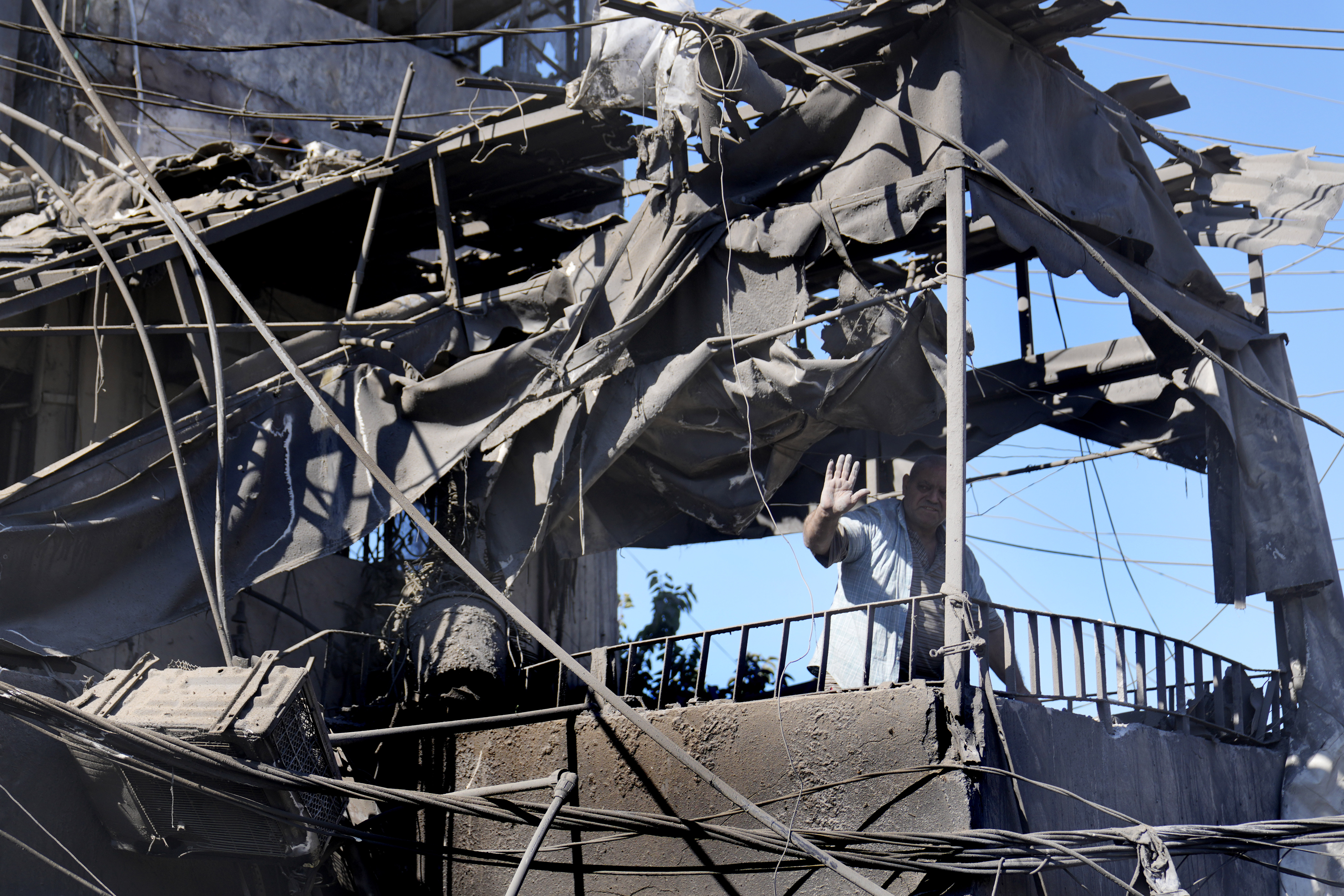 A man waves from his shattered house at the site of Israeli airstrikes that destroyed buildings facing the city's main government hospital in a densely-populated neighborhood, in southern Beirut, Lebanon, Tuesday, Oct. 22, 2024. (AP Photo/Hussein Malla)