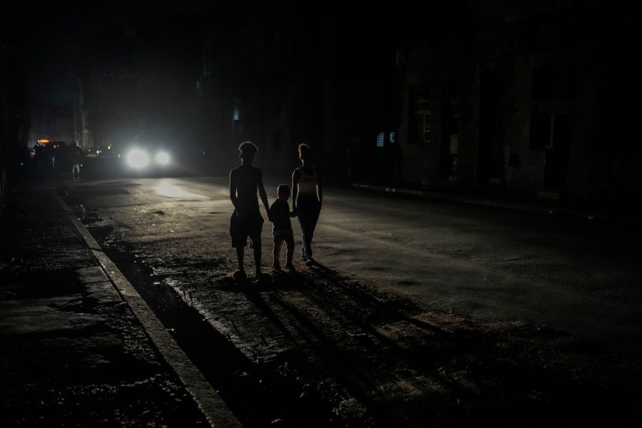 FILE - Residents are illuminated by the headlights of a car during a blackout after a major power plant failed in Havana, Cuba, Oct. 18, 2024. (AP Photo/Ramon Espinosa, File)