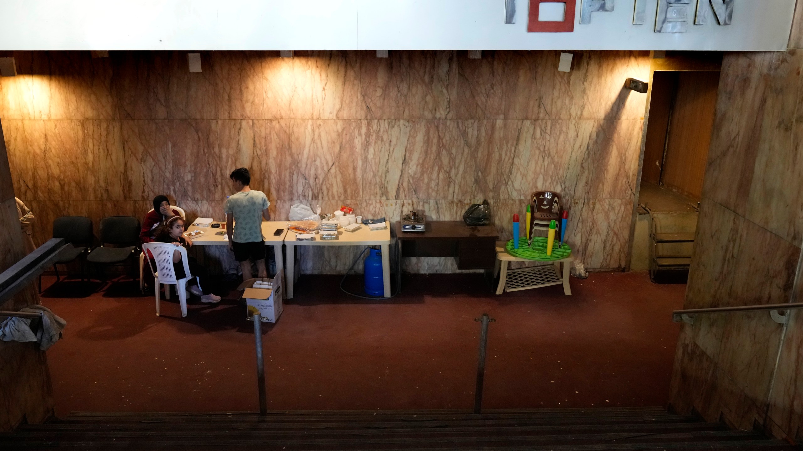 A displaced family, who fled the ongoing Hezbollah-Israel war in south Lebanon, gather inside one of Beirut's oldest and best known movie theatres, Le Colisee, where they are settled now, in Beirut, Lebanon, Tuesday, Oct. 22, 2024. (AP Photo/Hussein Malla)