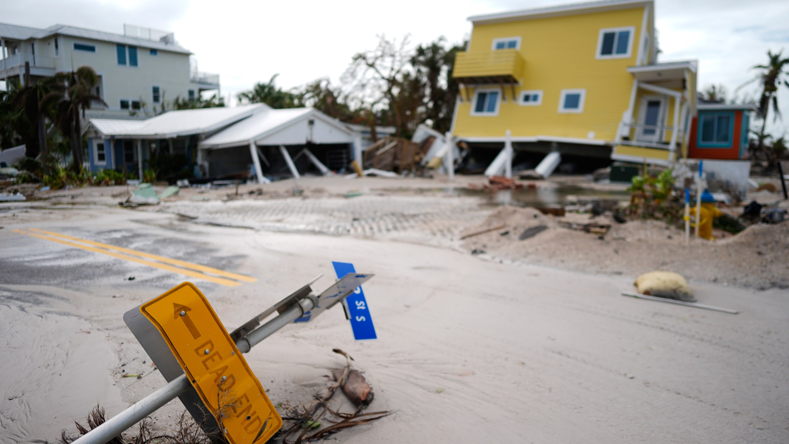 FILE - A house sits toppled off its stilts after the passage of Hurricane Milton, alongside an empty lot where a home was swept away by Hurricane Helene, in Bradenton Beach on Anna Maria Island, Fla., Oct. 10, 2024. (AP Photo/Rebecca Blackwell, File)