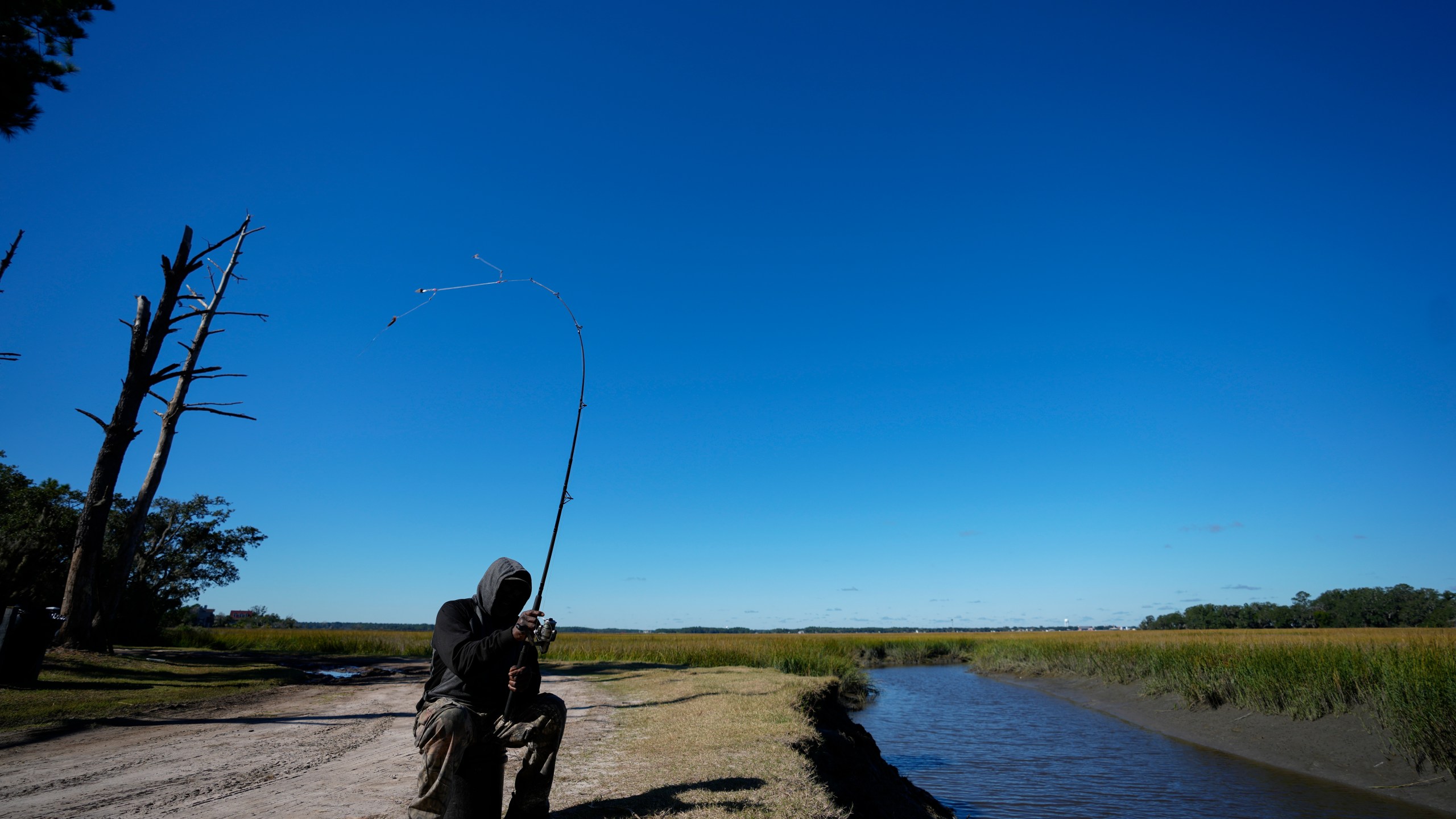 FILE - Gullah Geechee fisherman Ricky Wright casts his line as he fishes for bass in a marsh waterway with eroded banks on St. Helena Island, S.C., Sunday, Oct. 31, 2021. (AP Photo/Rebecca Blackwell, File)