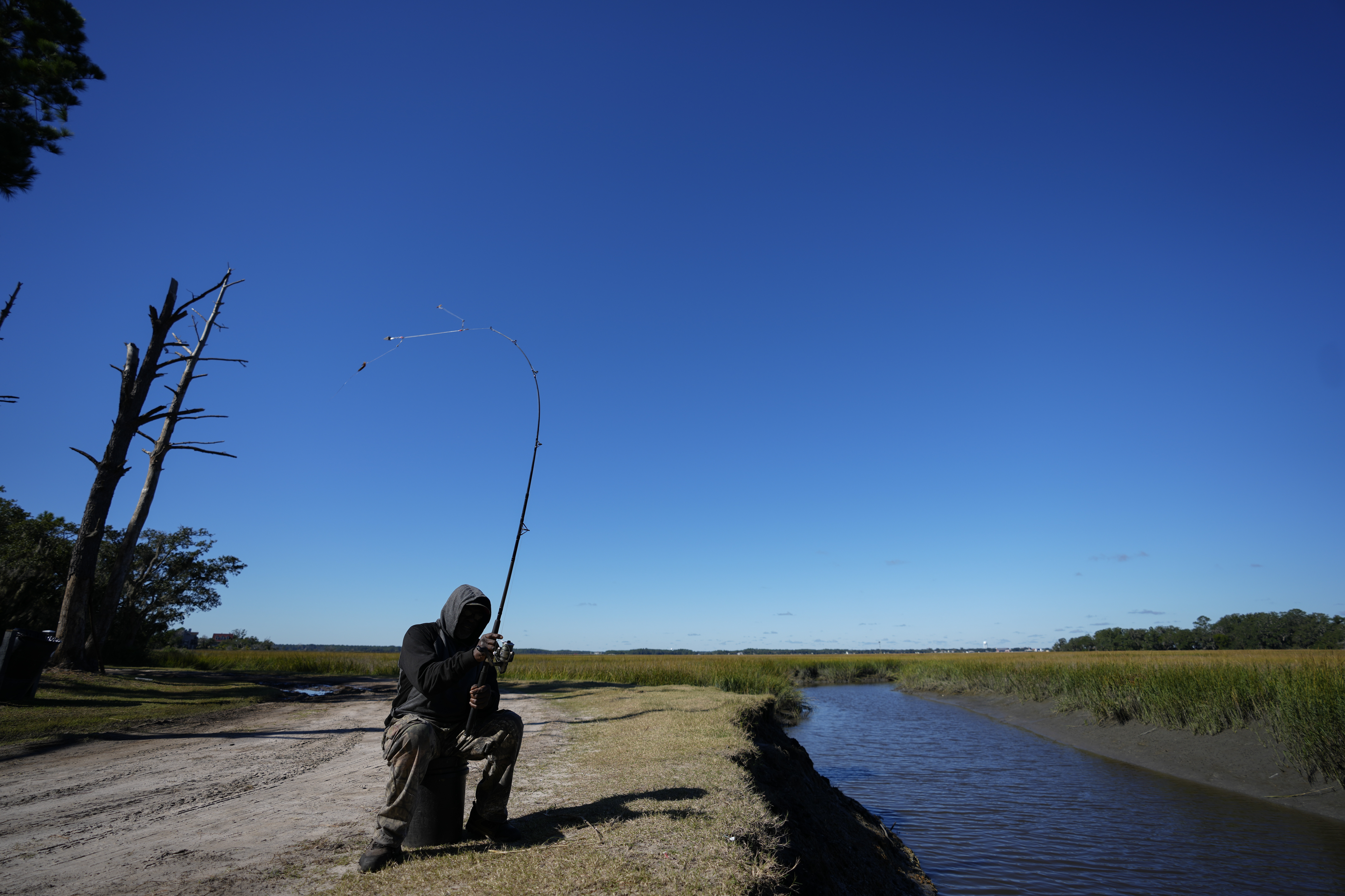 FILE - Gullah Geechee fisherman Ricky Wright casts his line as he fishes for bass in a marsh waterway with eroded banks on St. Helena Island, S.C., Sunday, Oct. 31, 2021. (AP Photo/Rebecca Blackwell, File)